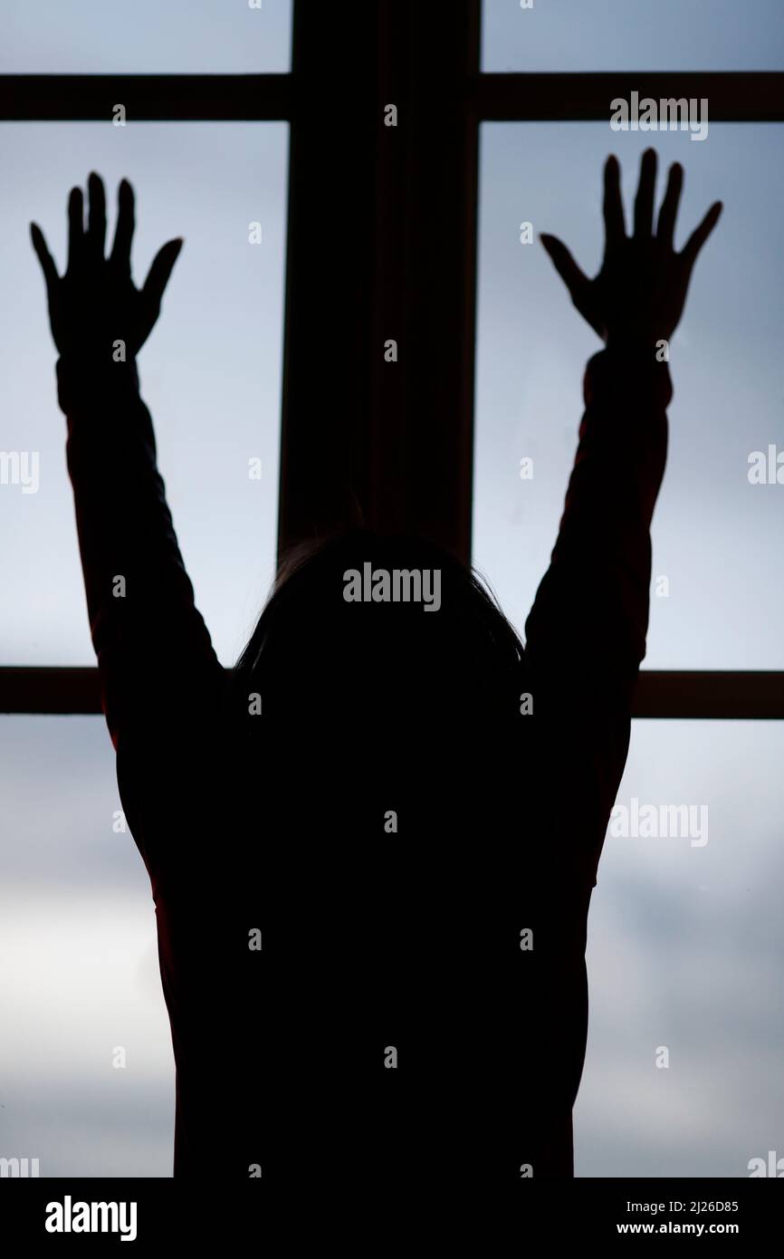 Silhouette della donna che guarda fuori dalla finestra. Foto Stock