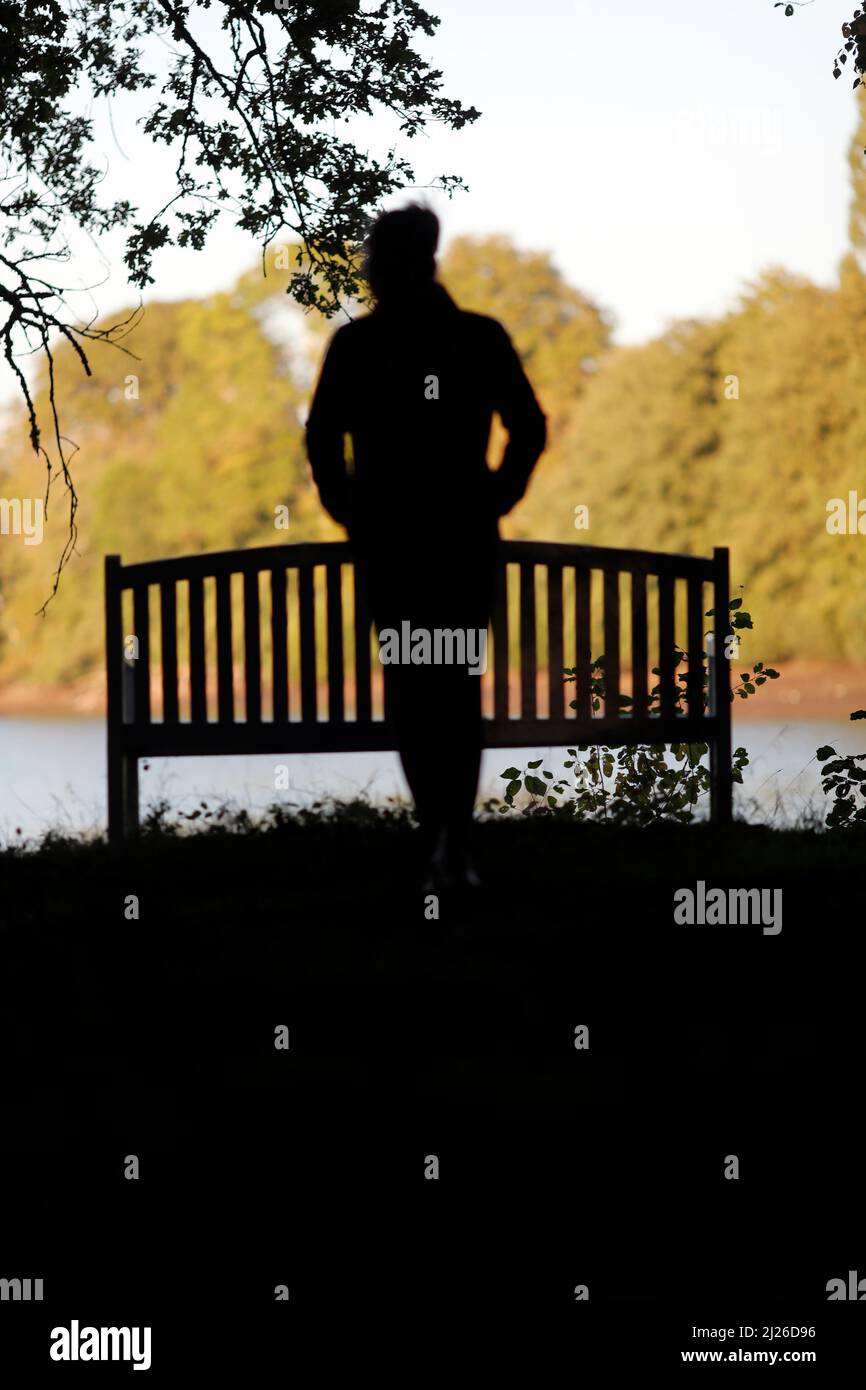 Silhouette sfocata di una donna che cammina da sola nel parco. Foto Stock