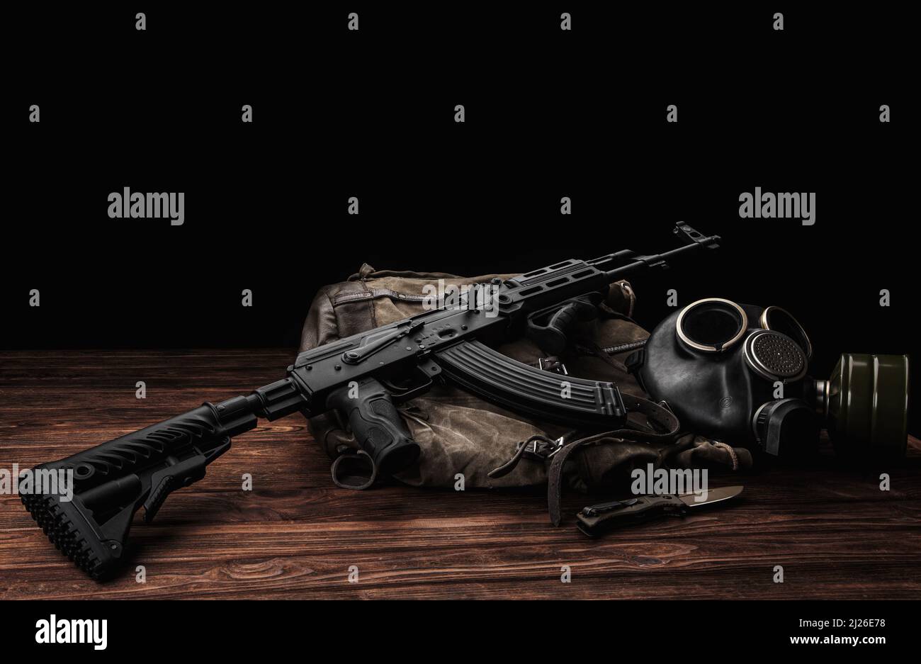 Carbina sovietica in kit corpo moderno. Armi della Russia e dell'Unione Sovietica. Classico fucile d'assalto AK sovietico e maschera a gas su sfondo di legno. Foto Stock