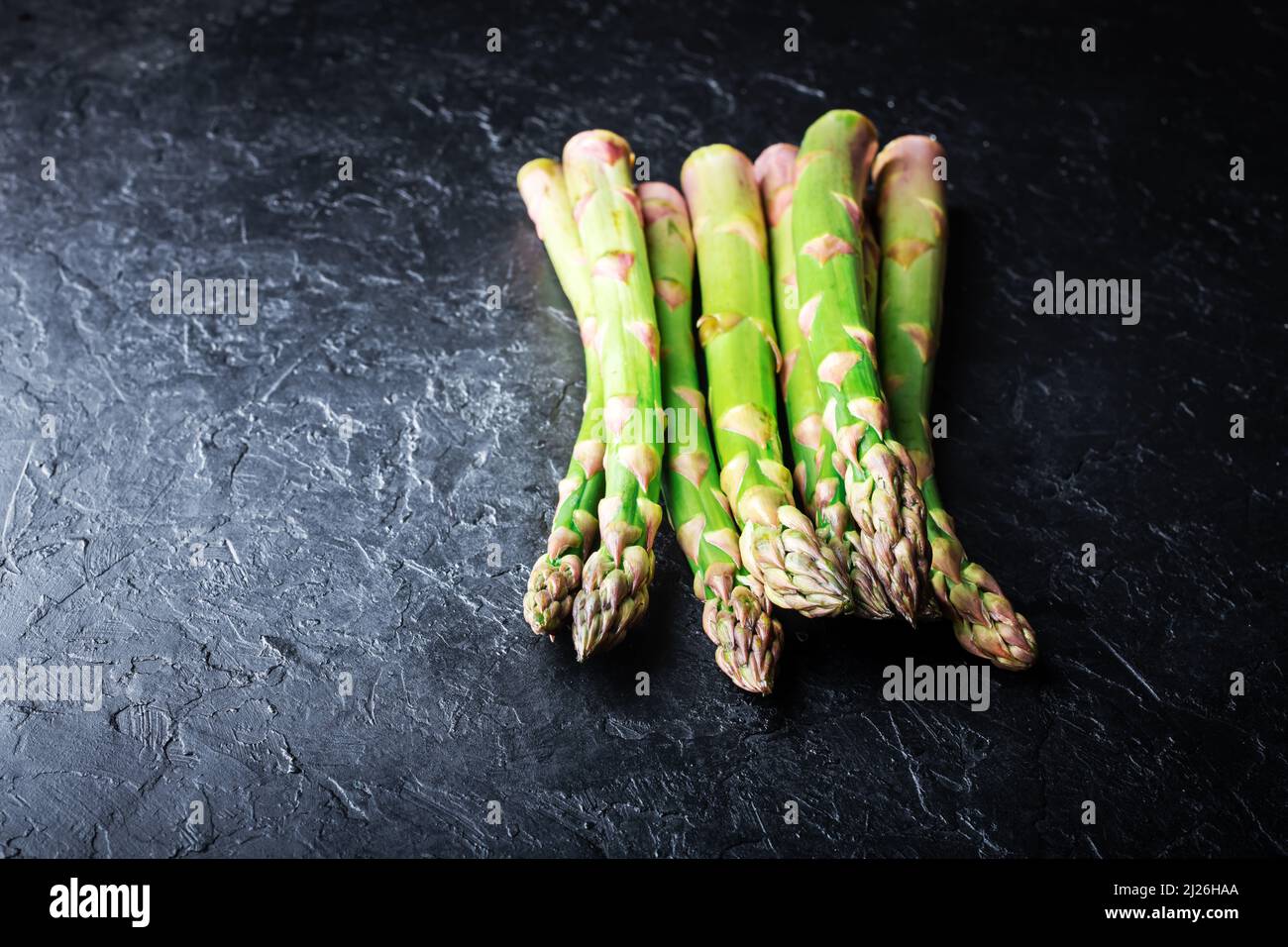 Germogli di asparagi verdi su tavola nera vista dall'alto piatto. Fotografia alimentare Foto Stock