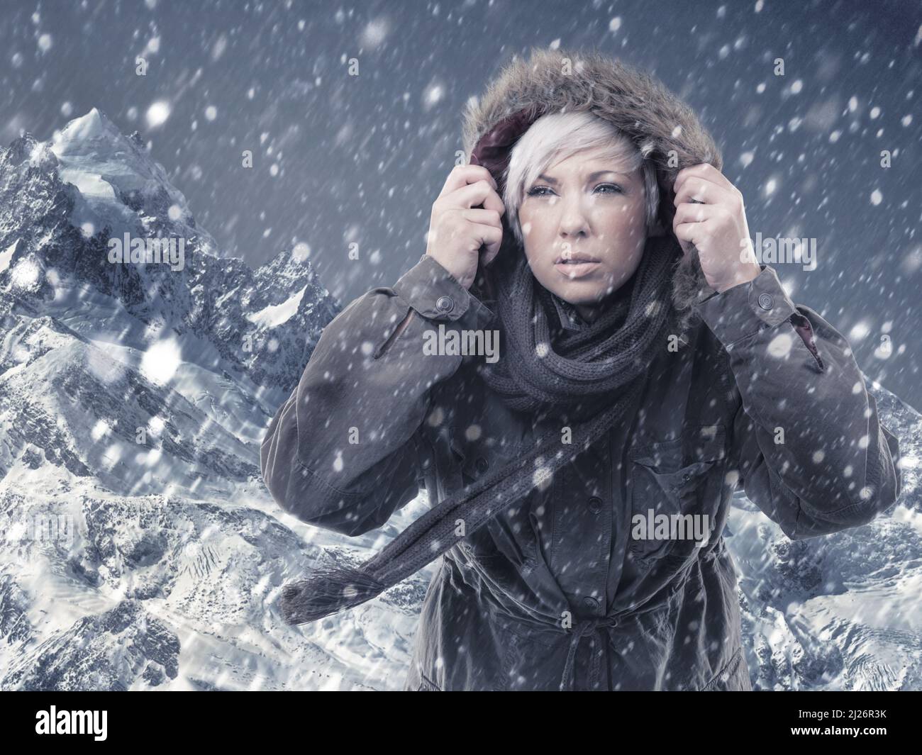 Affrontare le condizioni per raggiungere la cima. Scatto corto di una giovane donna attraente escursioni in mezzo a una tempesta di neve. Foto Stock