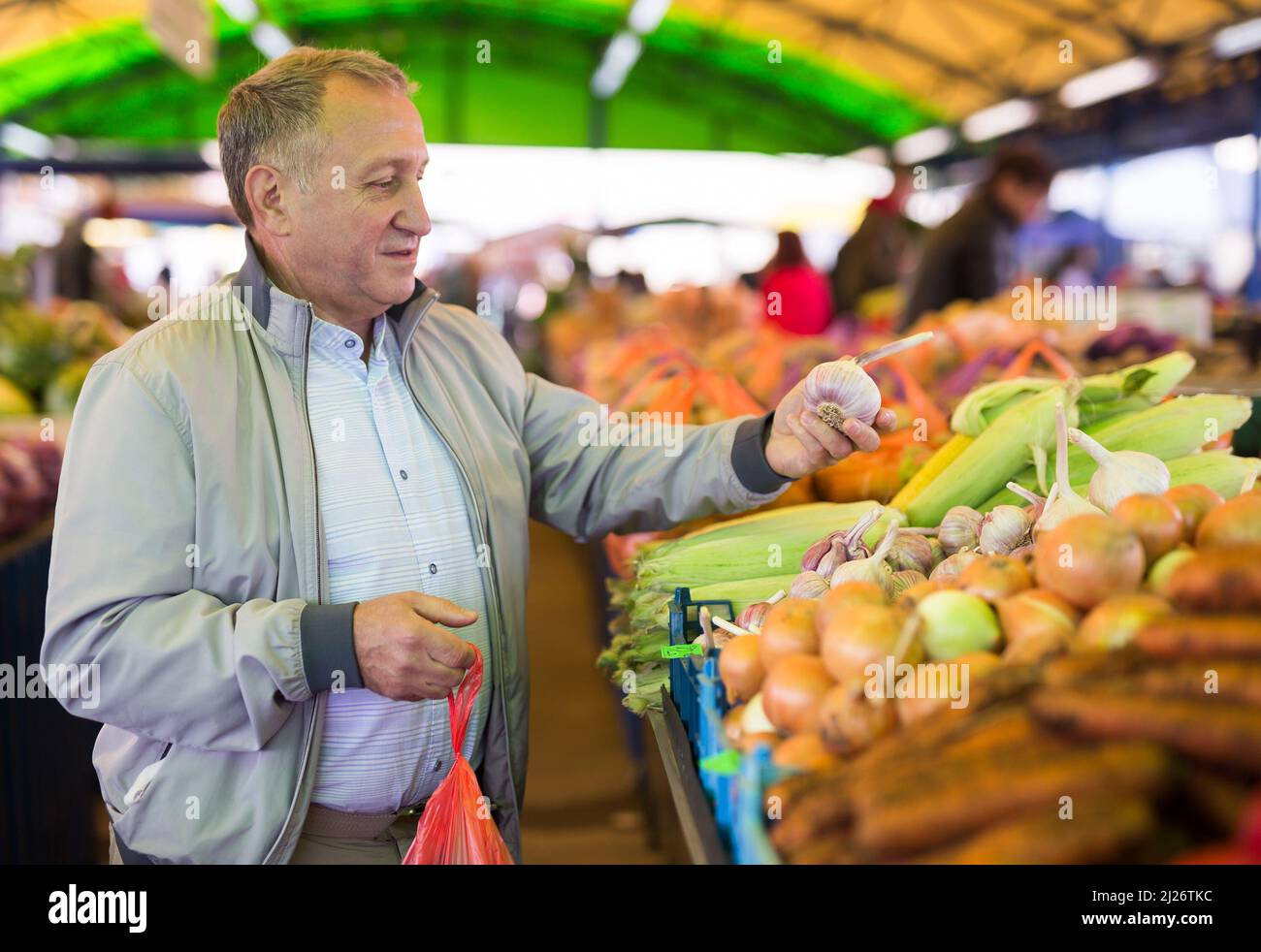 Uomo di mezza età che acquista aglio sul mercato Foto Stock