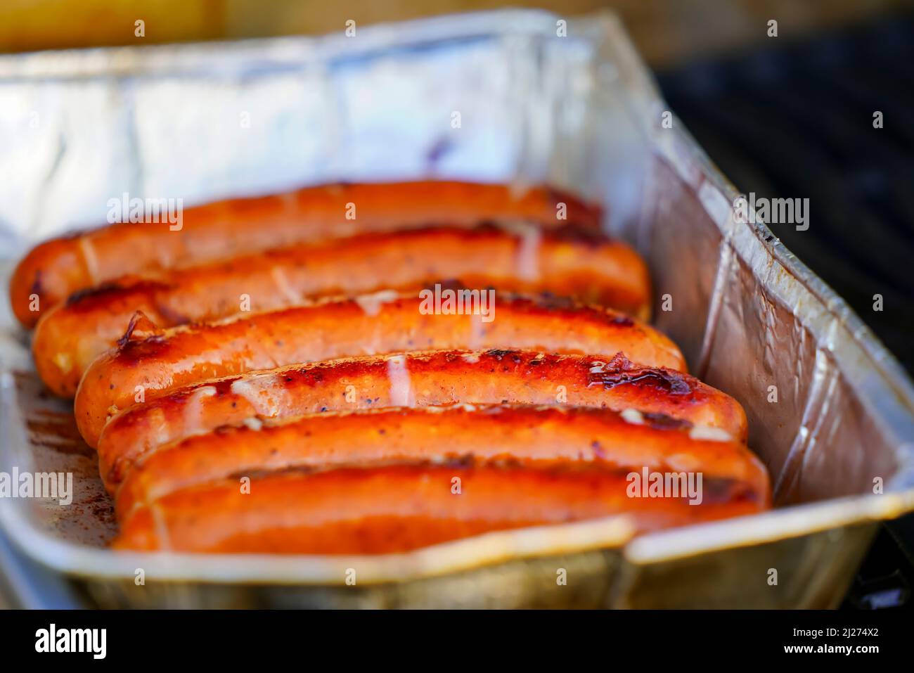 Burned Juicy salsiccia barbecue Sizzle on con sale e Black Peppers per pranzo barbecue alla griglia per picnic in estate. Bratwurst o Hot Dogs alla griglia. Foto Stock