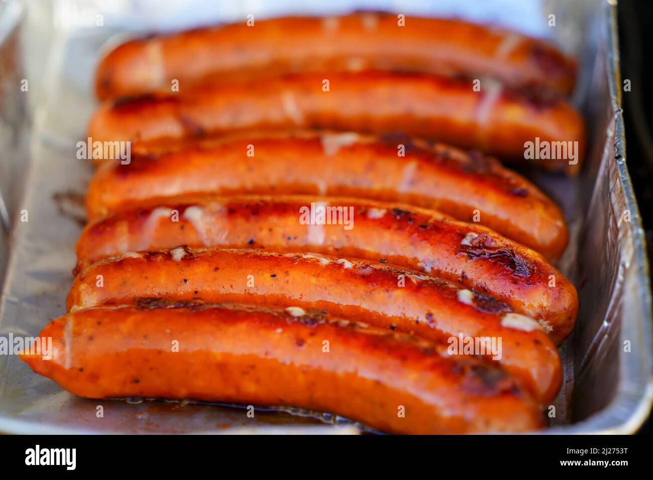 Burned Juicy salsiccia barbecue Sizzle on con sale e Black Peppers per pranzo barbecue alla griglia per picnic in estate. Bratwurst o Hot Dogs alla griglia. Foto Stock