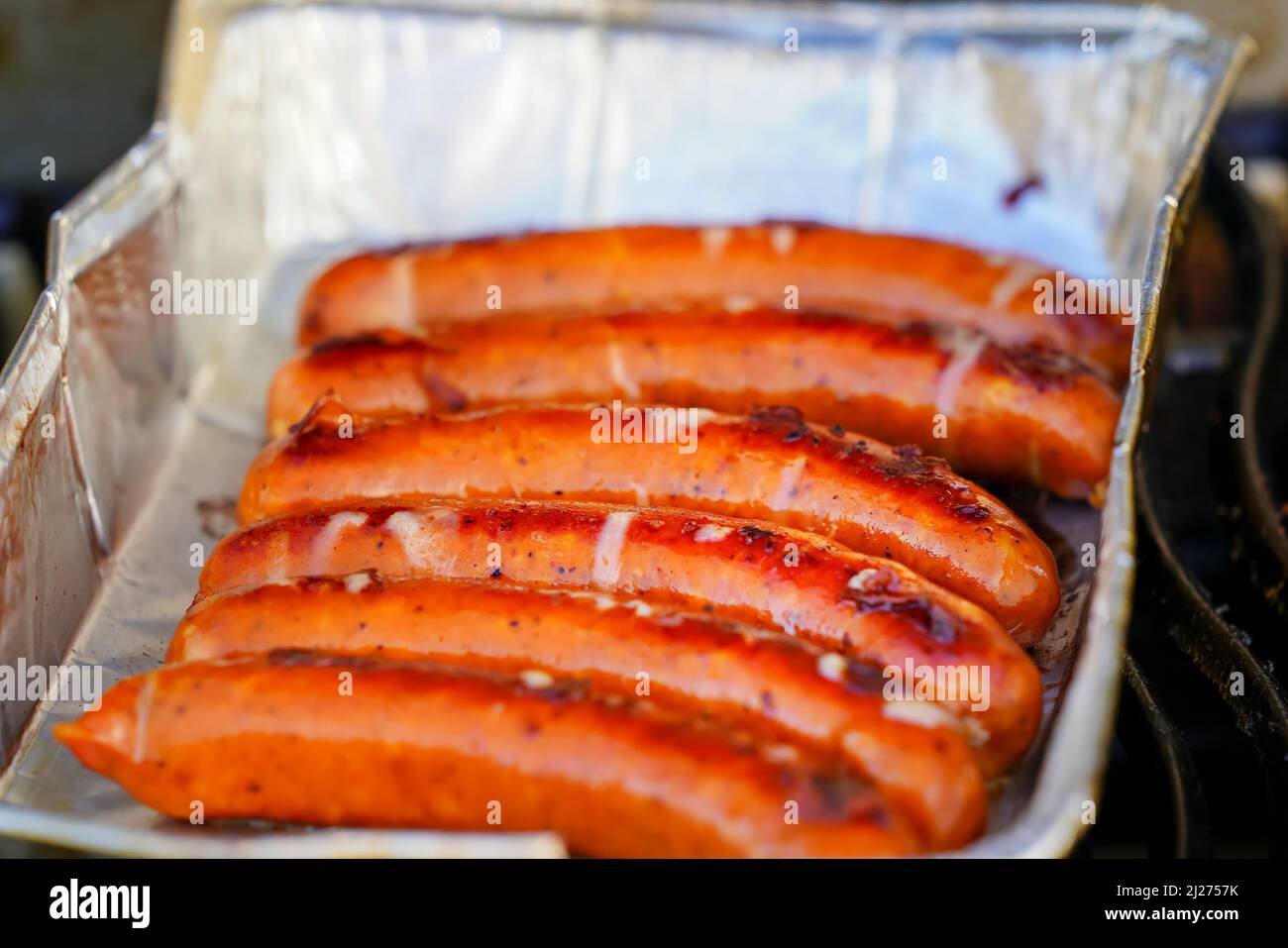 Burned Juicy salsiccia barbecue Sizzle on con sale e Black Peppers per pranzo barbecue alla griglia per picnic in estate. Bratwurst o Hot Dogs alla griglia. Foto Stock