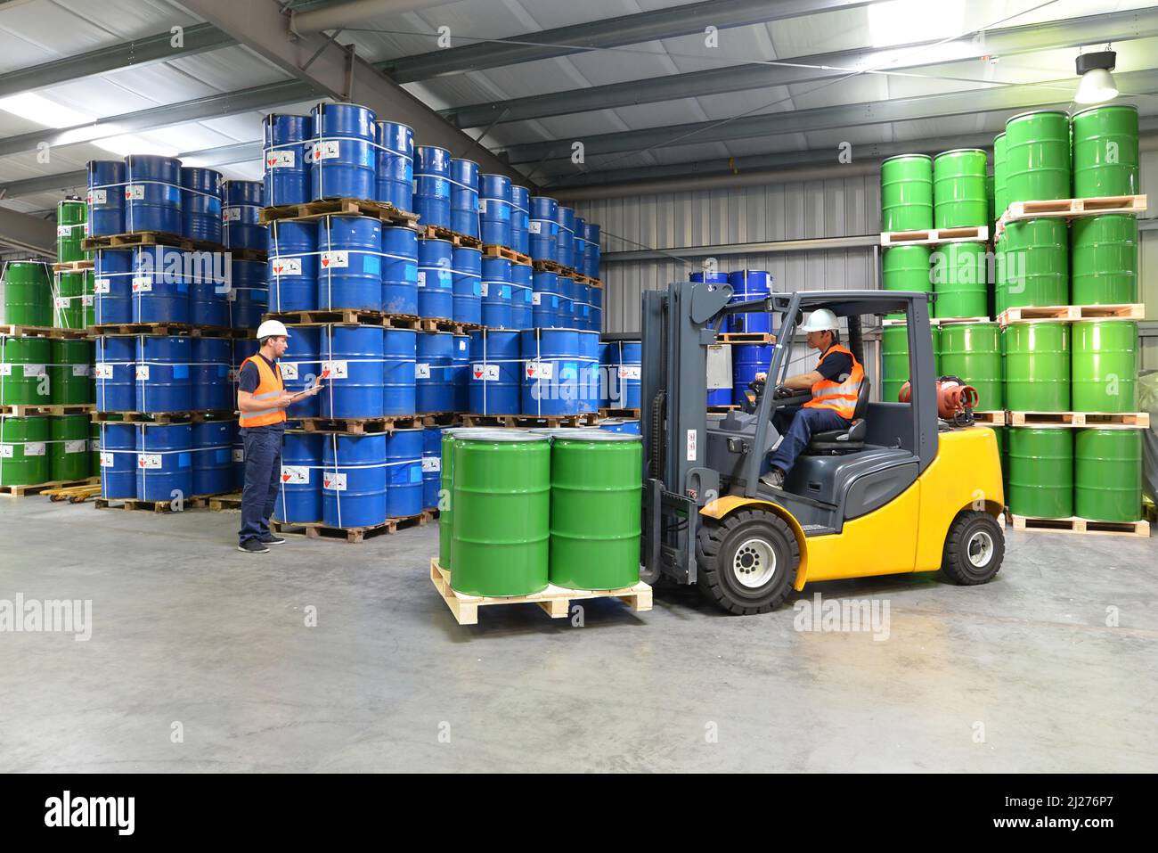 Gruppo di lavoratori nell'industria logistica lavorare in un magazzino con prodotti chimici - Sollevamento del carrello Foto Stock