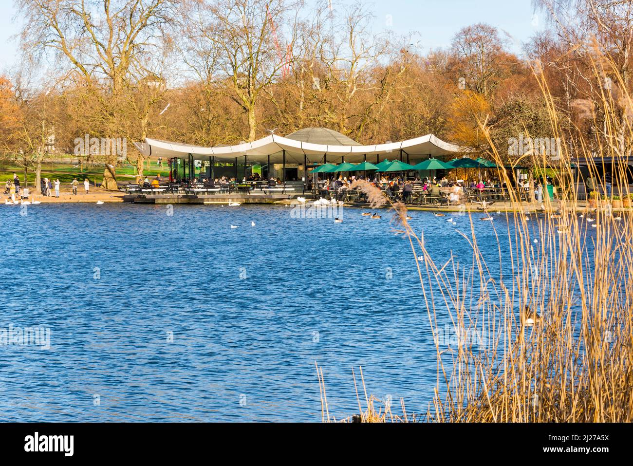 Le persone si rilassano e si godono all'aperto in un caffè, il Serpentine Bar and Kitchen, a Hyde Park, Londra, in una luminosa giornata di sole invernale. Foto Stock
