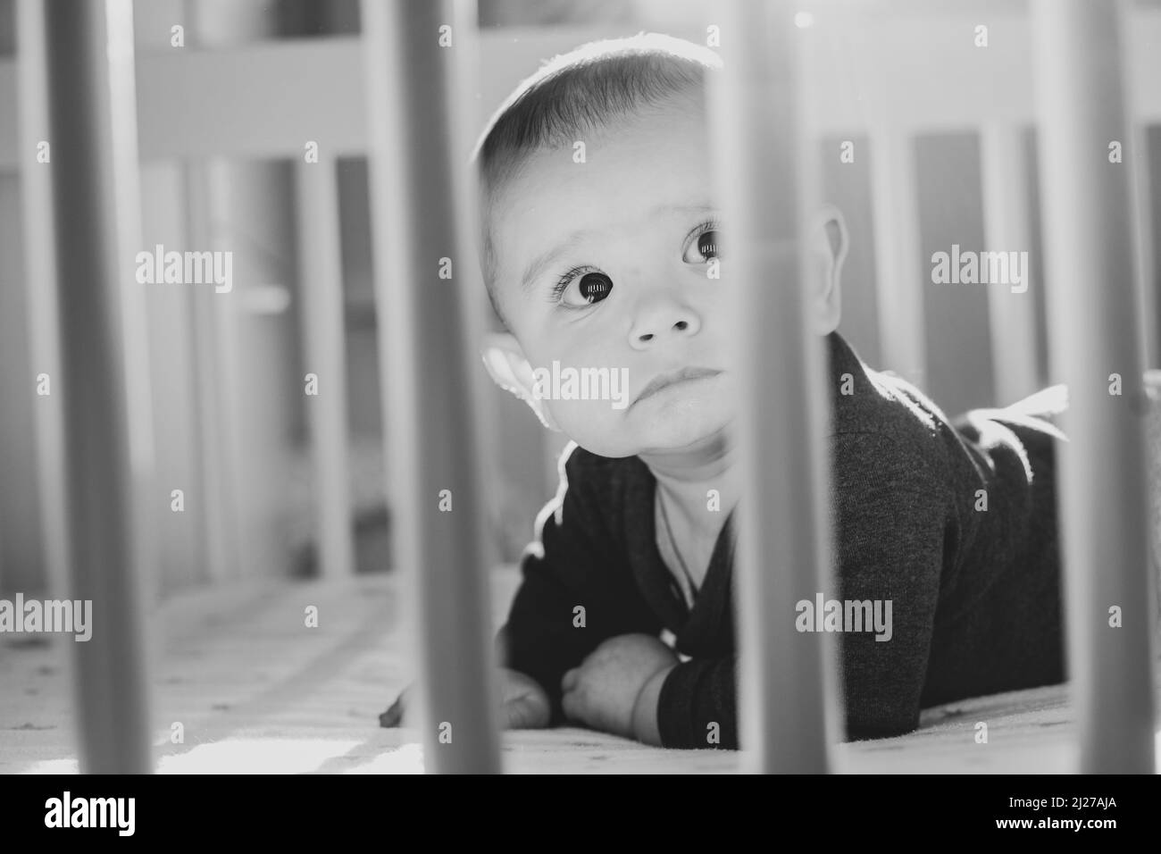 Un primo piano monocromatico di un bambino che guarda in su dalla sua greppia Foto Stock