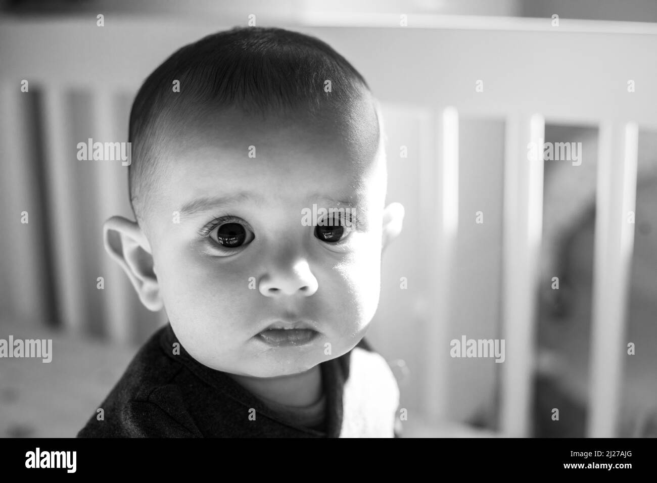 Un primo piano monocromatico di un bambino che guarda in su dalla sua greppia Foto Stock