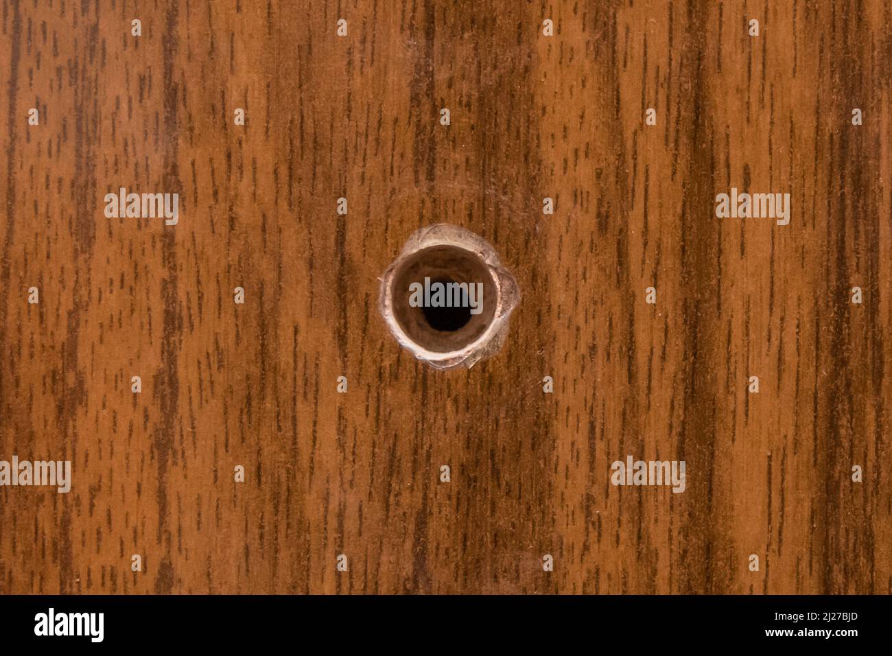 Foro rotondo sulla superficie in legno del truciolare rotto del legno pressato danneggiato, primo piano. Foto Stock