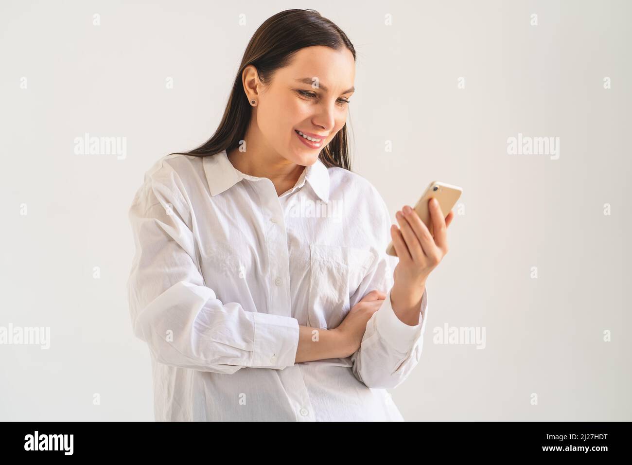 Giovane ragazza o donna in maglietta bianca usa lo smartphone per social media, messaggi e app. Moderna tecnologia di comunicazione internet nella vita di tutti i giorni. Foto Stock