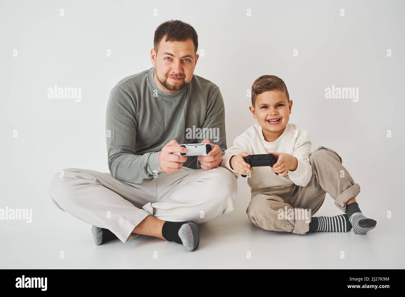 Paternità. Padre e figlio giocare gioco console gamepad ridere e divertirsi insieme. I giocatori giocano con i videogame per computer Foto Stock