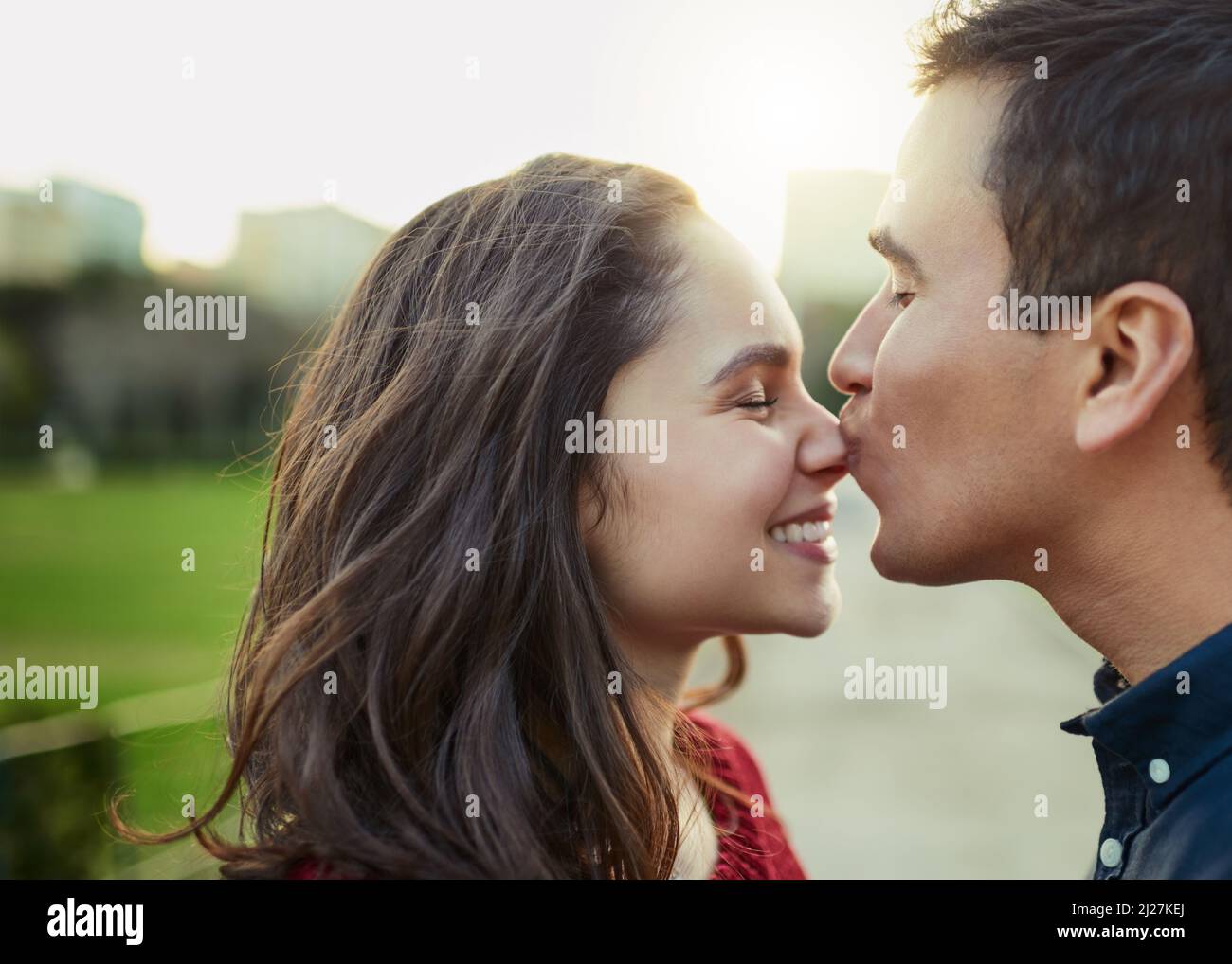 Amore, niente altro necessario. Scatto di un giovane che bacia la sua ragazza sul naso all'aperto. Foto Stock