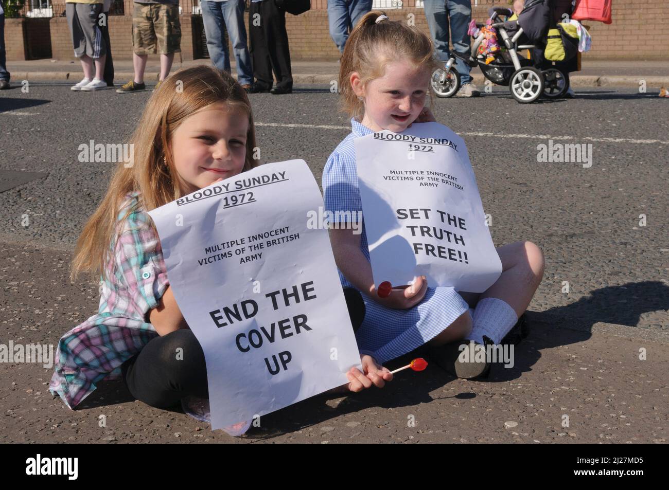 14/06/2010, Short Strand, Belfast, Irlanda del Nord. I bambini tengono in mano i manifesti di protesta contro una bandiera nera prima del rapporto Saville sulla Domenica Bloody Foto Stock
