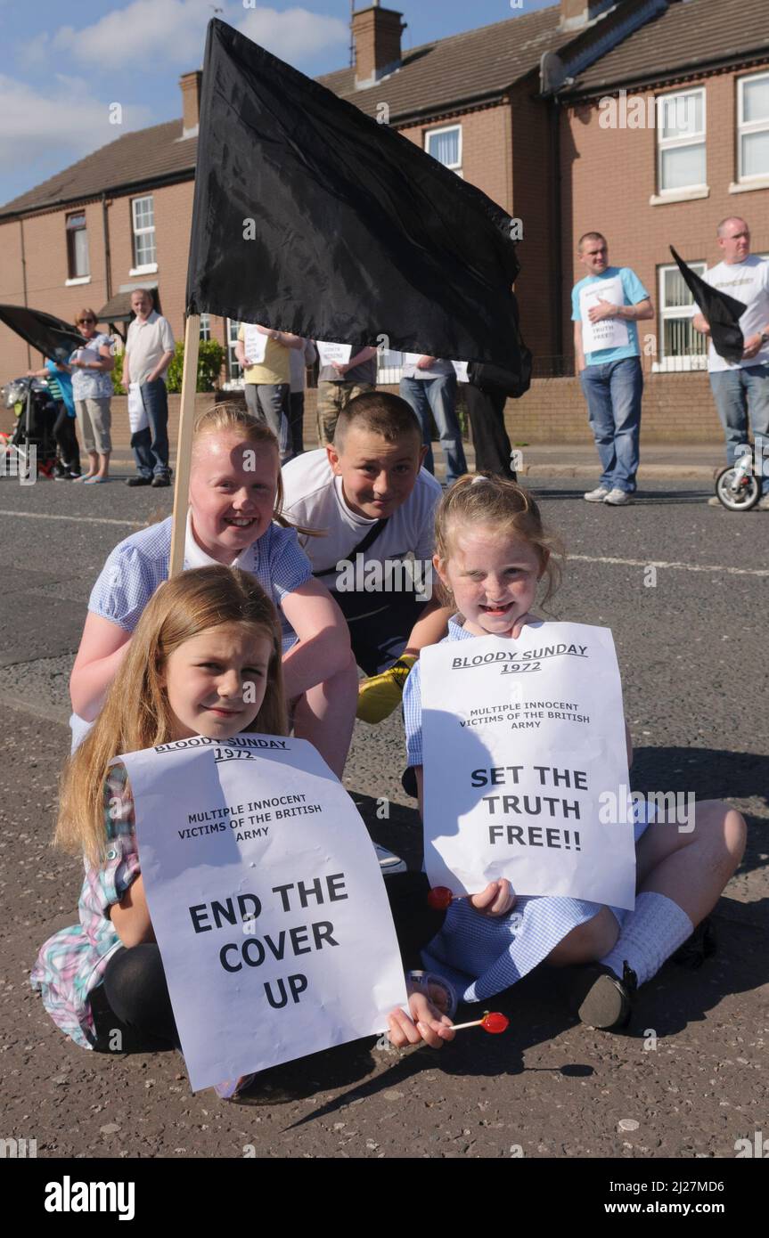 14/06/2010, Short Strand, Belfast, Irlanda del Nord. I bambini tengono in mano i manifesti di protesta contro una bandiera nera prima del rapporto Saville sulla Domenica Bloody Foto Stock