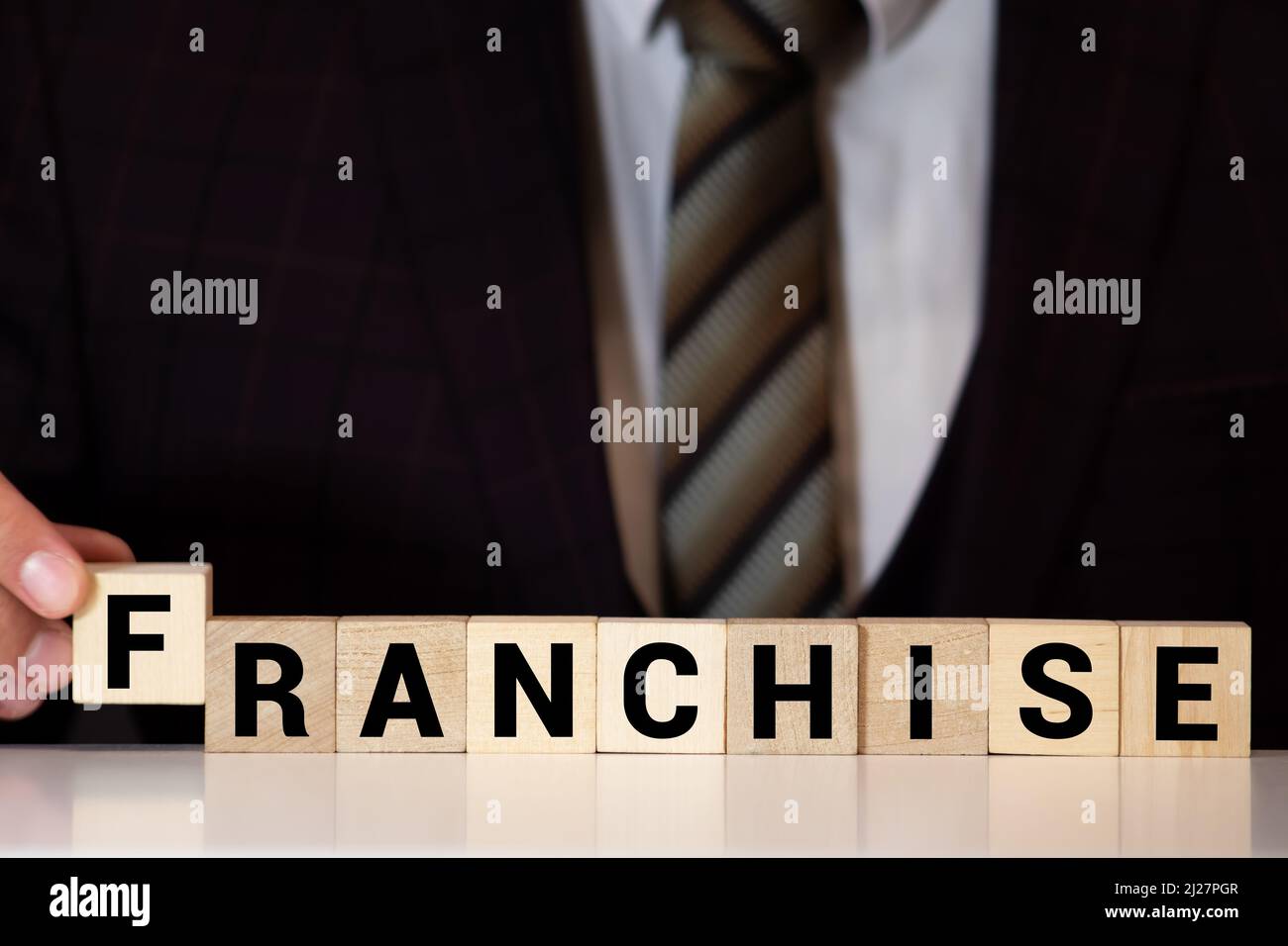 Primo piano su notebook su tavola di legno sfondo, concentrarsi sui blocchi di legno con lettere rendendo il testo di franchising. Concetto di immagine. Laptop, bicchieri, penna e mob Foto Stock