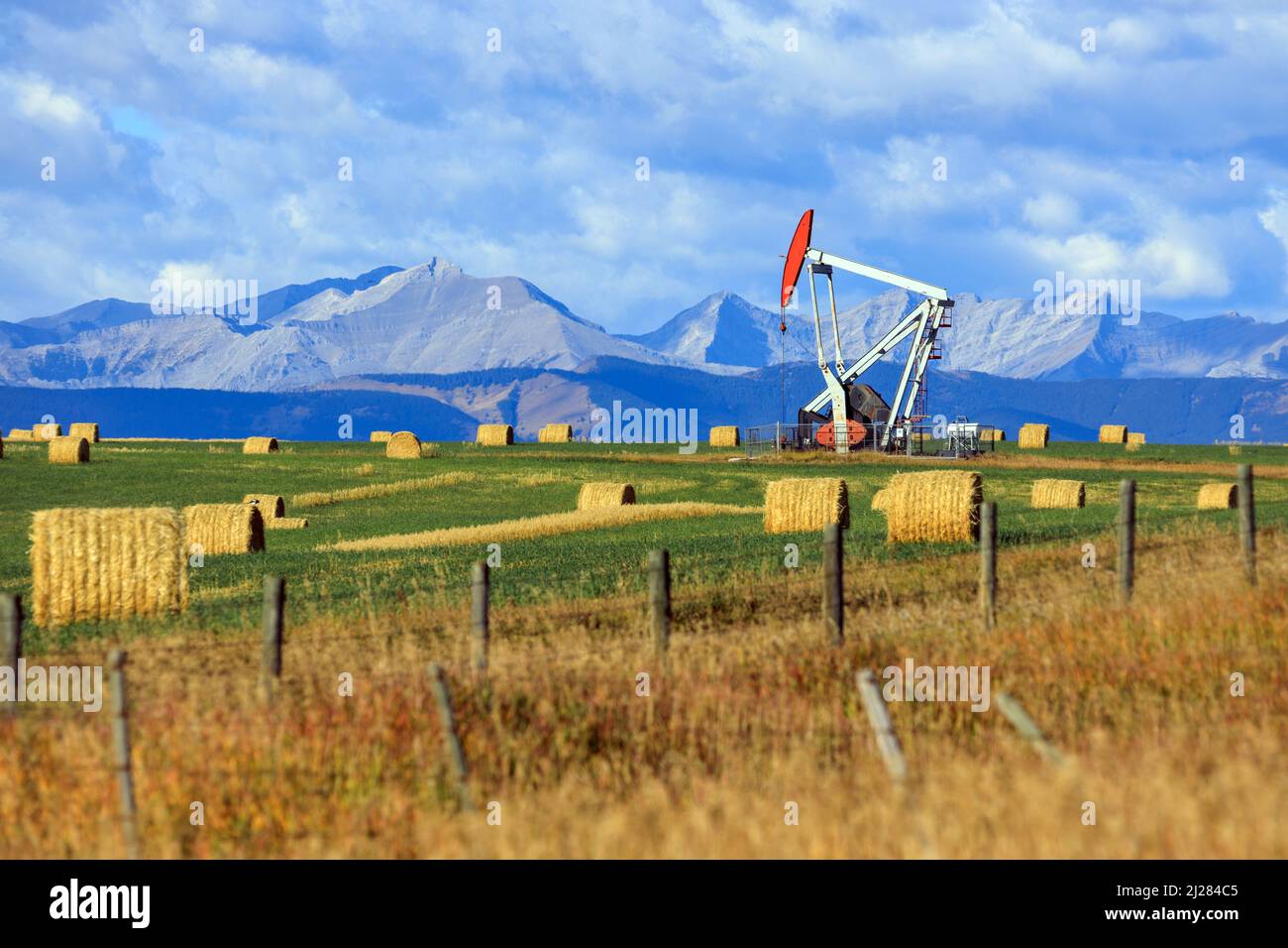 Un carro di perforazione per pickjack dell'industria petrolifera e del gas nelle praterie canadesi con le Montagne Rocciose canadesi ad Alberta, Canada. Foto Stock