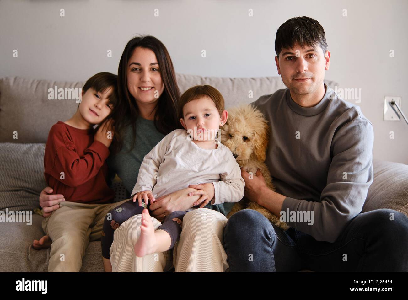 Ritratto di una famiglia felice seduta con il loro cane sul divano a casa. Foto Stock