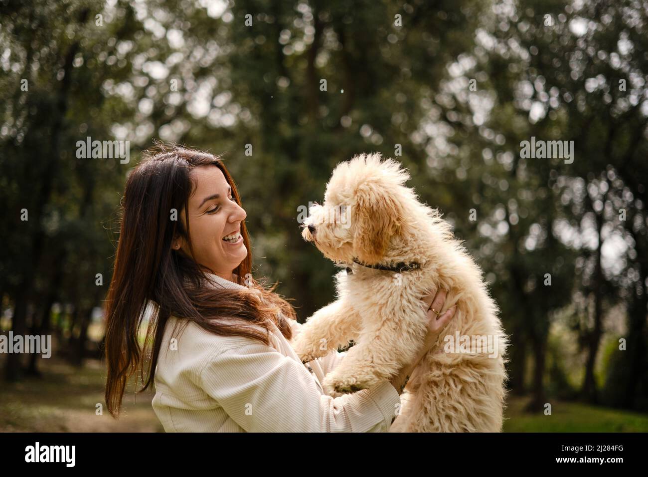 Donna felice che tiene il suo cane mentre si gode una giornata all'aperto nella natura. Foto Stock