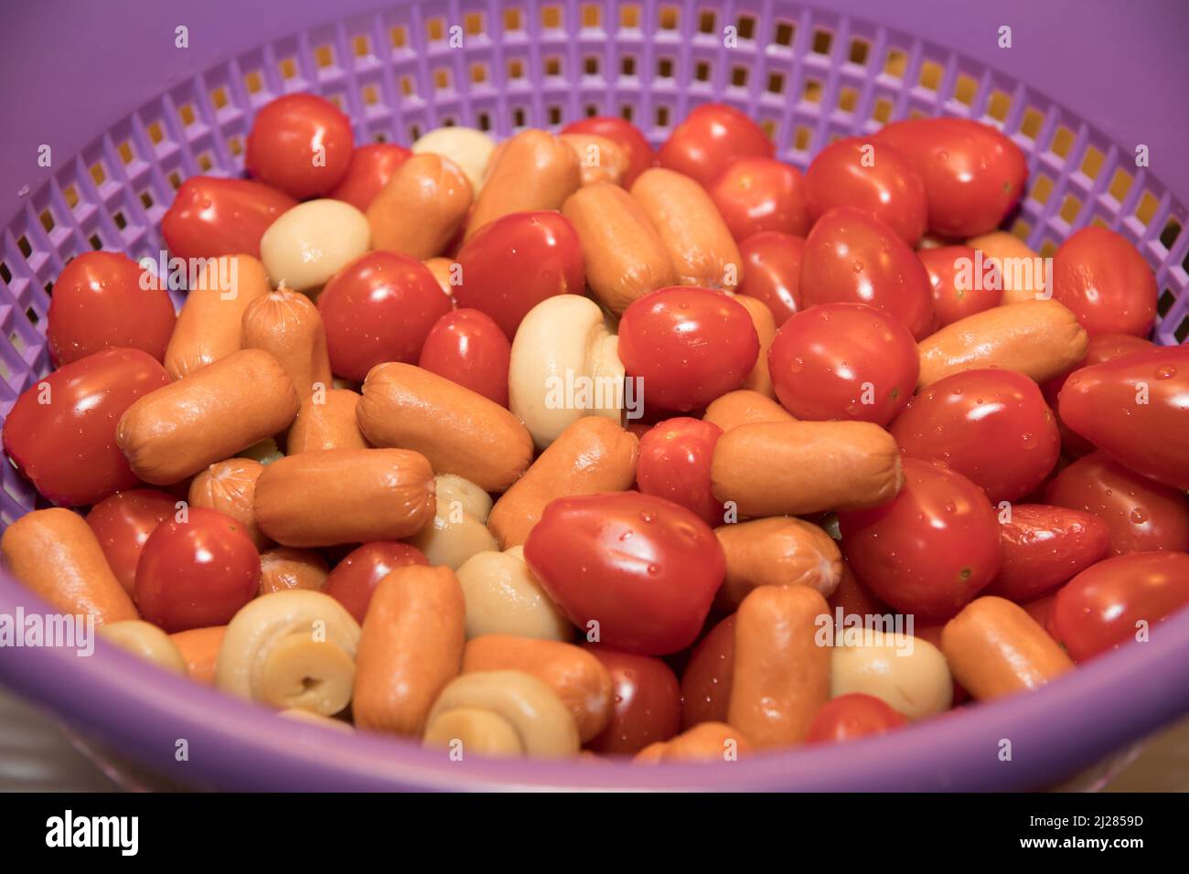 Un primo piano di un alimento prety colorato riempito in una ciotola viola a rete Foto Stock