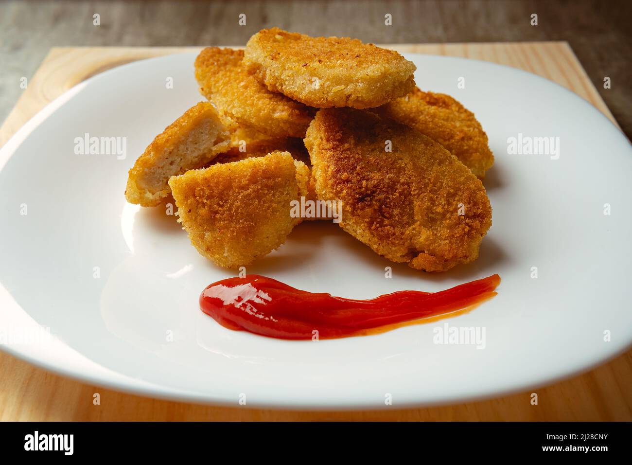 Pepite di pollo con pane fritto croccante, fondo in legno. Gustosi pepite di pollo, con salsa di pomodoro pronta a mangiare. Foto Stock