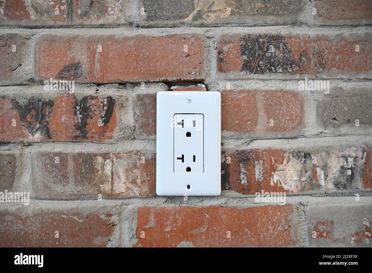 Un primo piano di una presa elettrica in un muro di mattoni Foto Stock