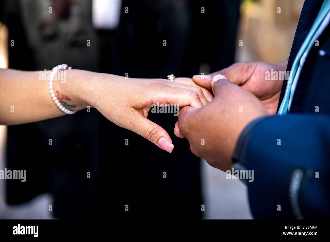 Indossare l'anello di messa sul dito della sposa primo piano di mani e anello Foto Stock