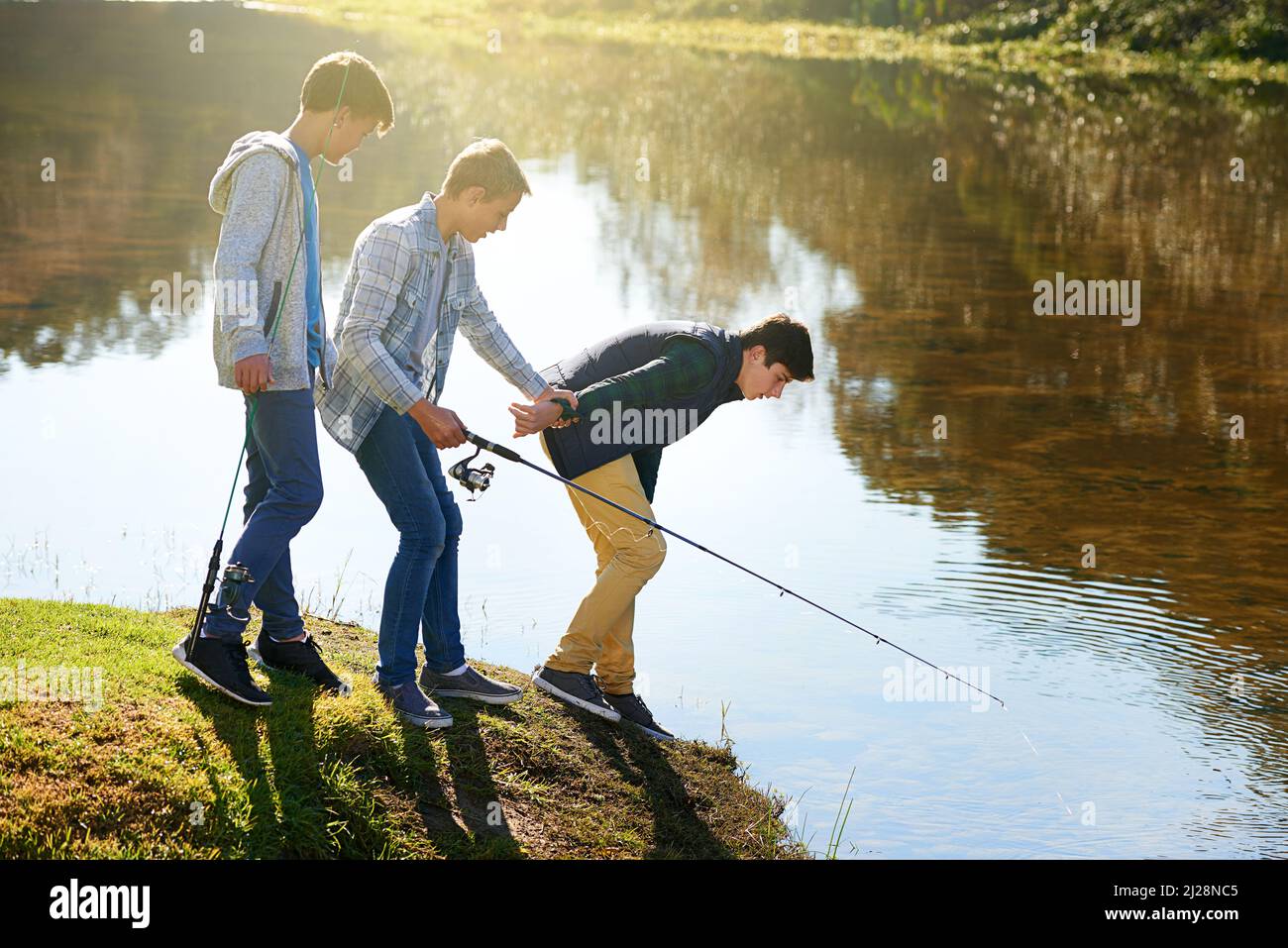 Lasciatemi dare un'occhiata Shot di un gruppo di ragazzi che pescano presso un lago. Foto Stock