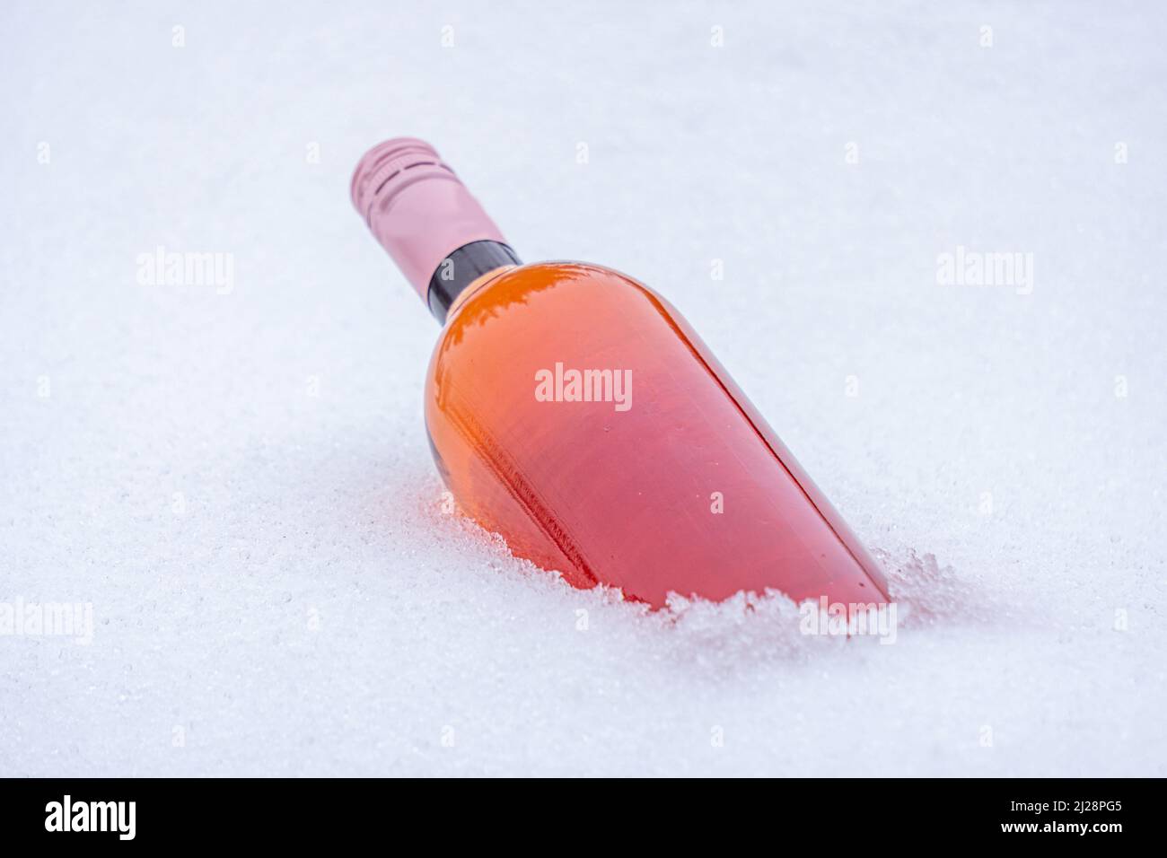 primo piano della bottiglia di vino rosa nella neve dopo una nevicata pesante nella zona. Foto Stock
