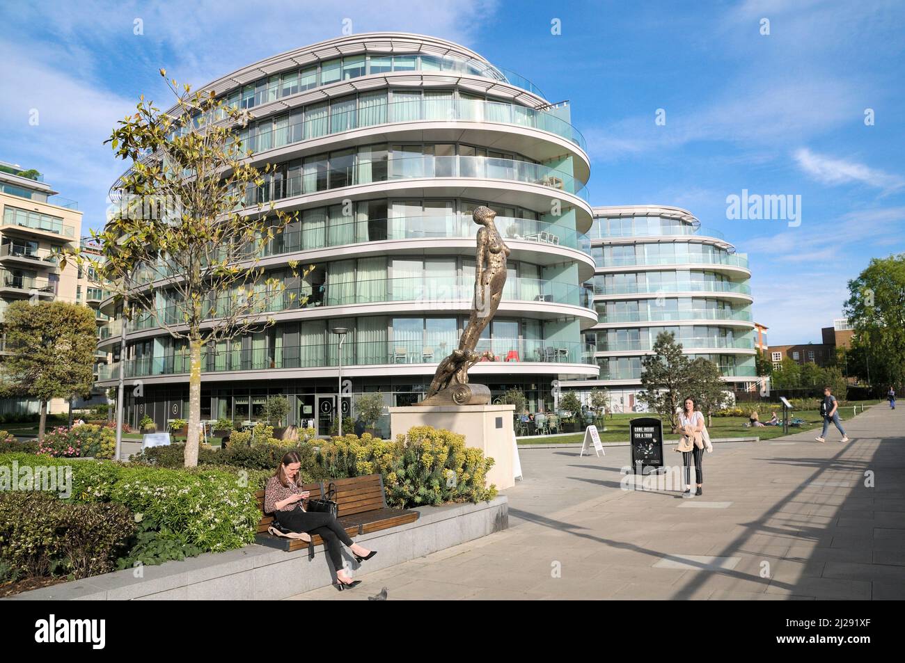 Moderni appartamenti lungo il fiume e sculture a testa di statuetta di Rick Kirby, Distillery Wharf, Fulham Reach, Hammersmith e Fulham, West London, Inghilterra, Regno Unito Foto Stock