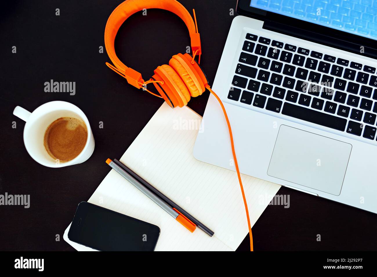 Benvenuti nel mondo del business moderno. Inquadratura ad alta angolazione di uno spazio di lavoro vuoto con un computer portatile, auricolari e notebook disposti su di esso. Foto Stock