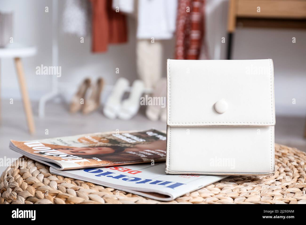Borsa elegante e riviste di moda sul pouf in camera Foto Stock