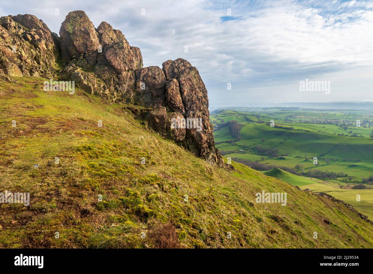 Rocce enormi che si affacciano sulla campagna dello Shropshire all'alba, paesaggio roccioso e colline coperte di erba, paesaggio suggestivo dalla collina ventosa. Foto Stock