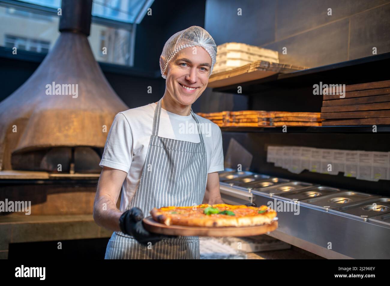 Uno chef in grembiule e cappellino per preparare la pizza Foto Stock
