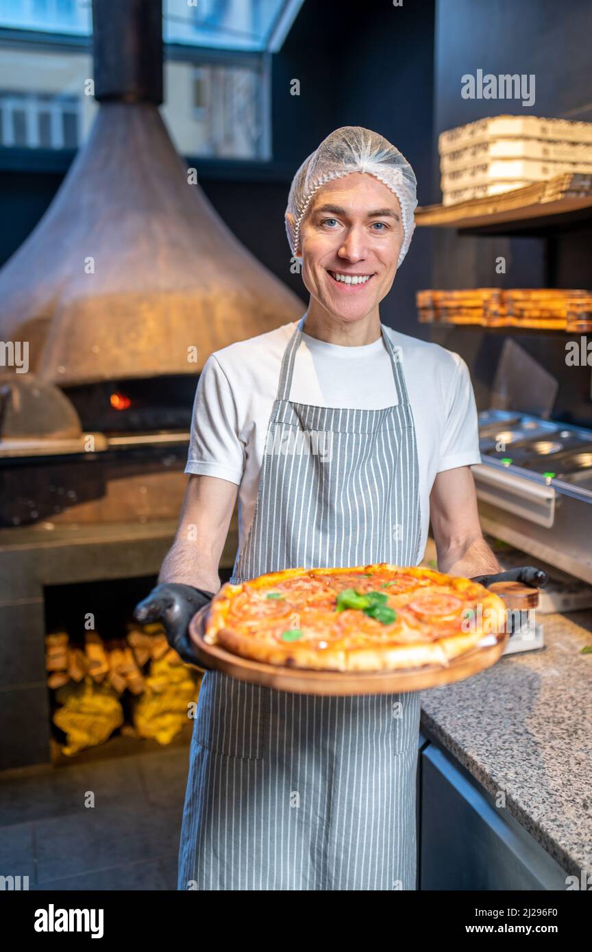 Uno chef in grembiule e cappellino per preparare la pizza Foto Stock