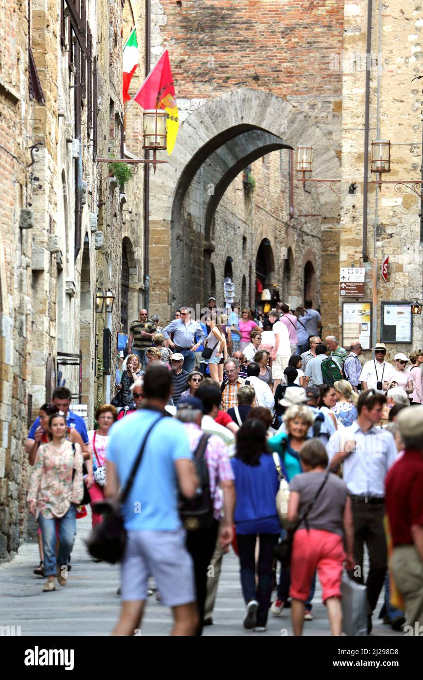 I turisti a piedi lungo via San Giovanni nella storica città toscana di San Gimignano in Italia Foto Stock