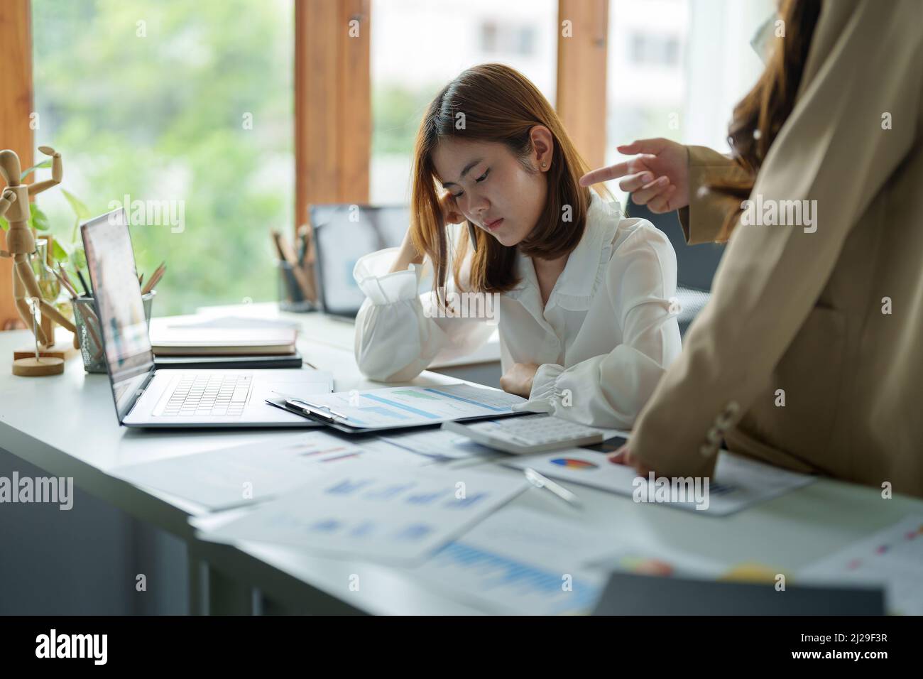 Giovane donna d'affari sensazione di essere seria, tenendo la testa mentre il suo capo si lamenta del lavoro. Foto Stock