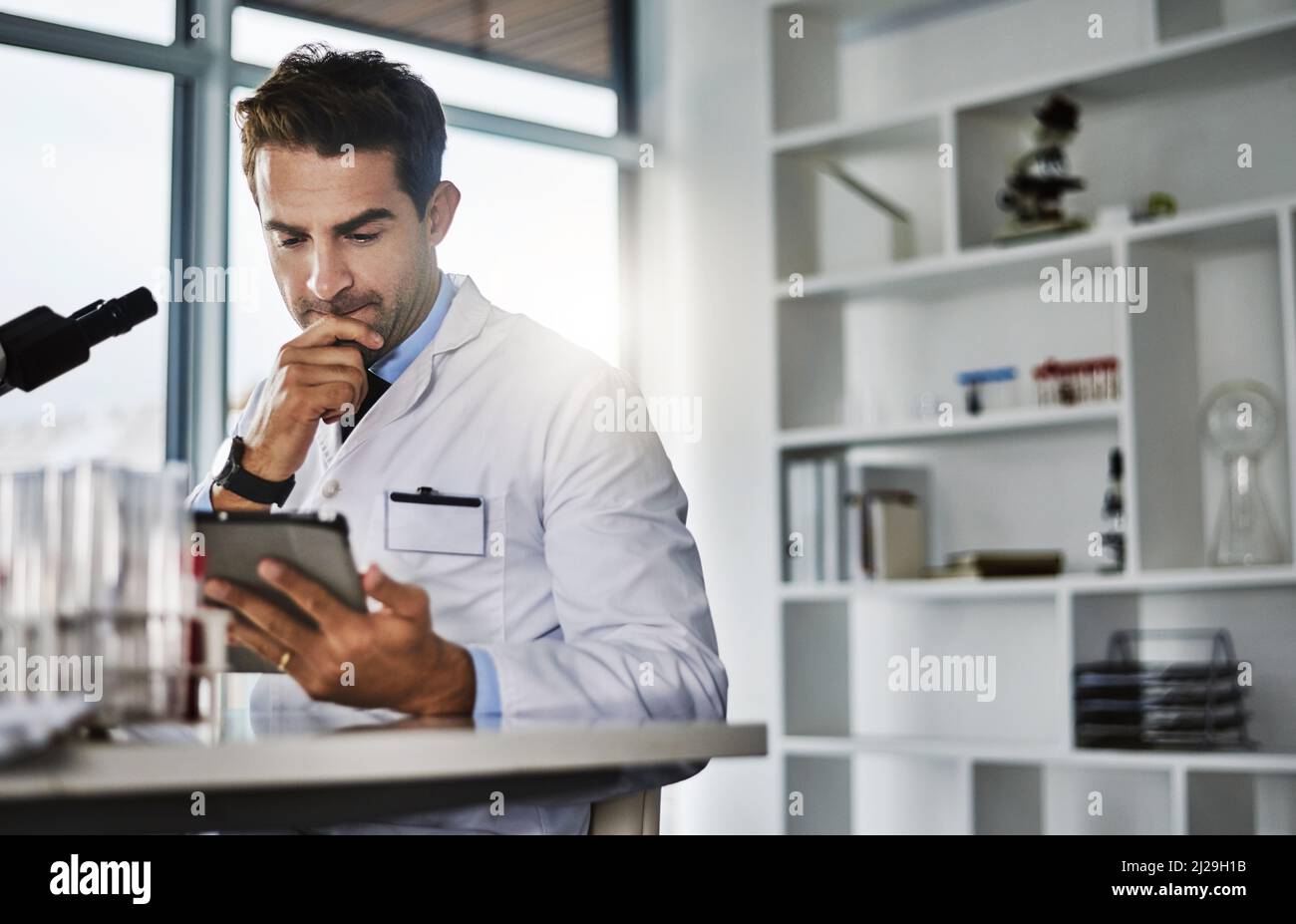 Devo pensarlo un po' di più. Foto di uno scienziato che utilizza un tablet digitale mentre lavora in laboratorio. Foto Stock