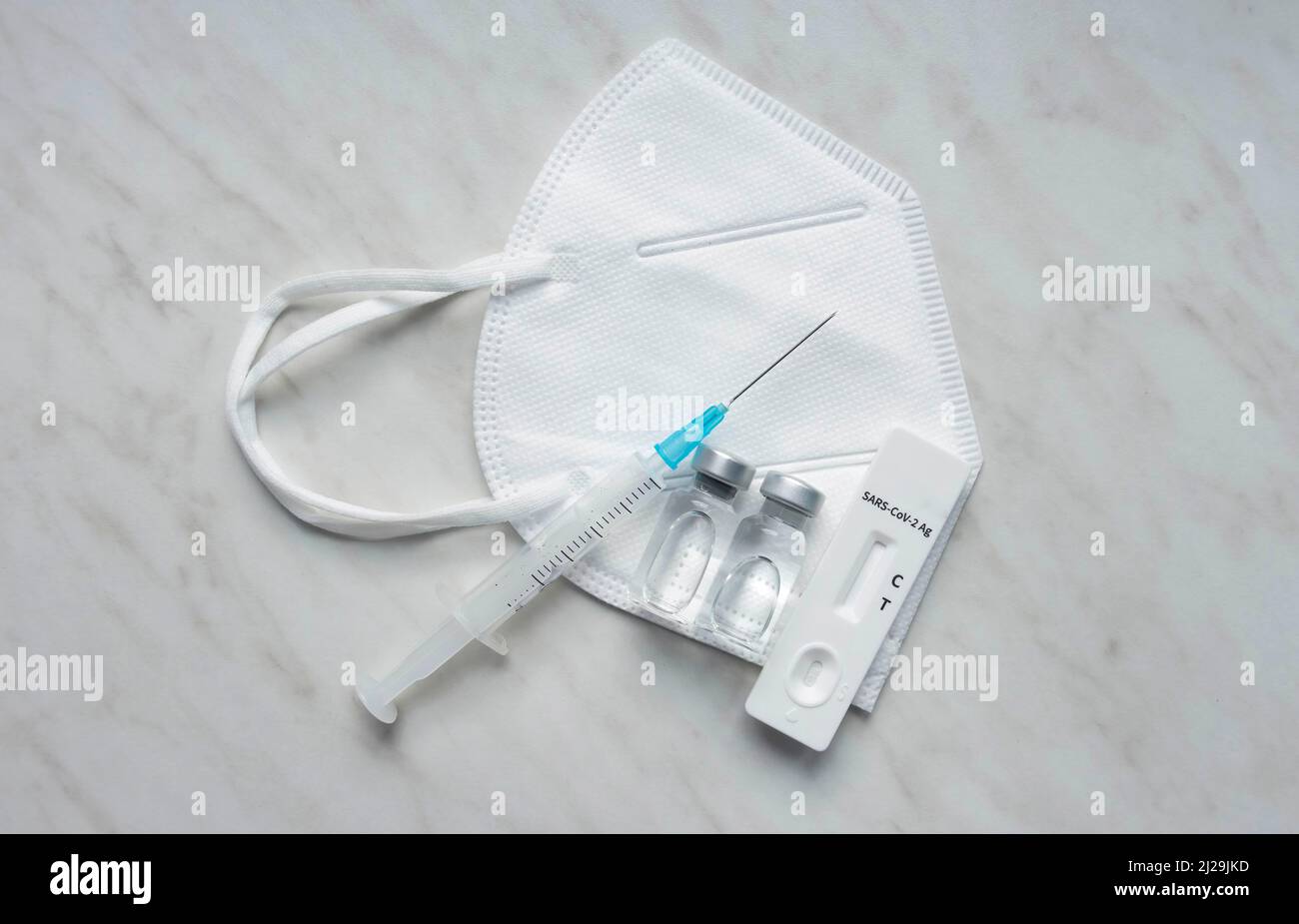 Maschera medica, test dell'antigene, flaconi di vaccino e siringa utilizzati per la prevenzione e il trattamento durante la pandemia di Coronavirus Covid 19 Foto Stock