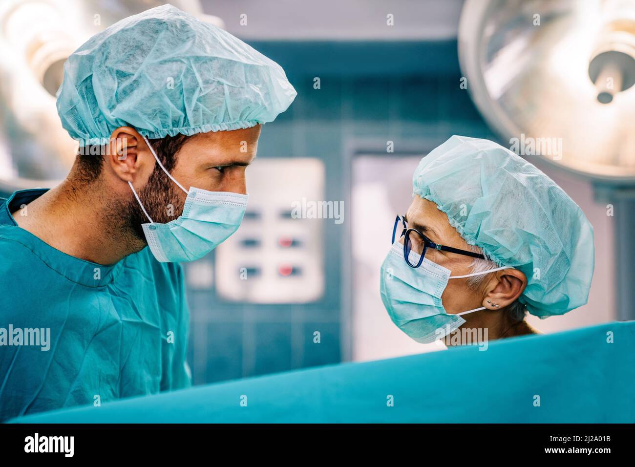 Team di chirurghi in sala operatoria che si preparano all'intervento chirurgico Foto Stock