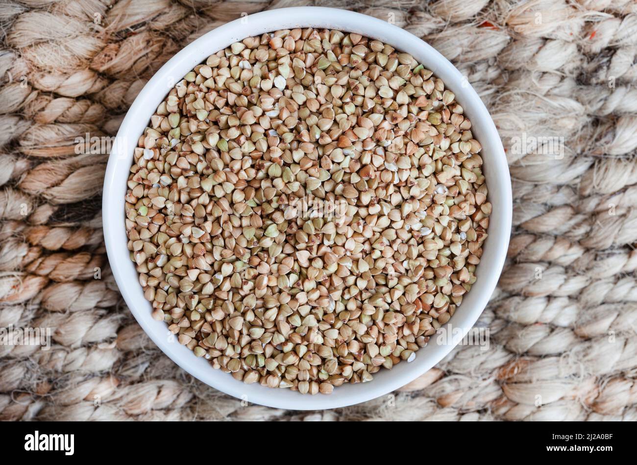 Ciotola piena di grano saraceno intero su superficie rustica con spazio di copia Foto Stock