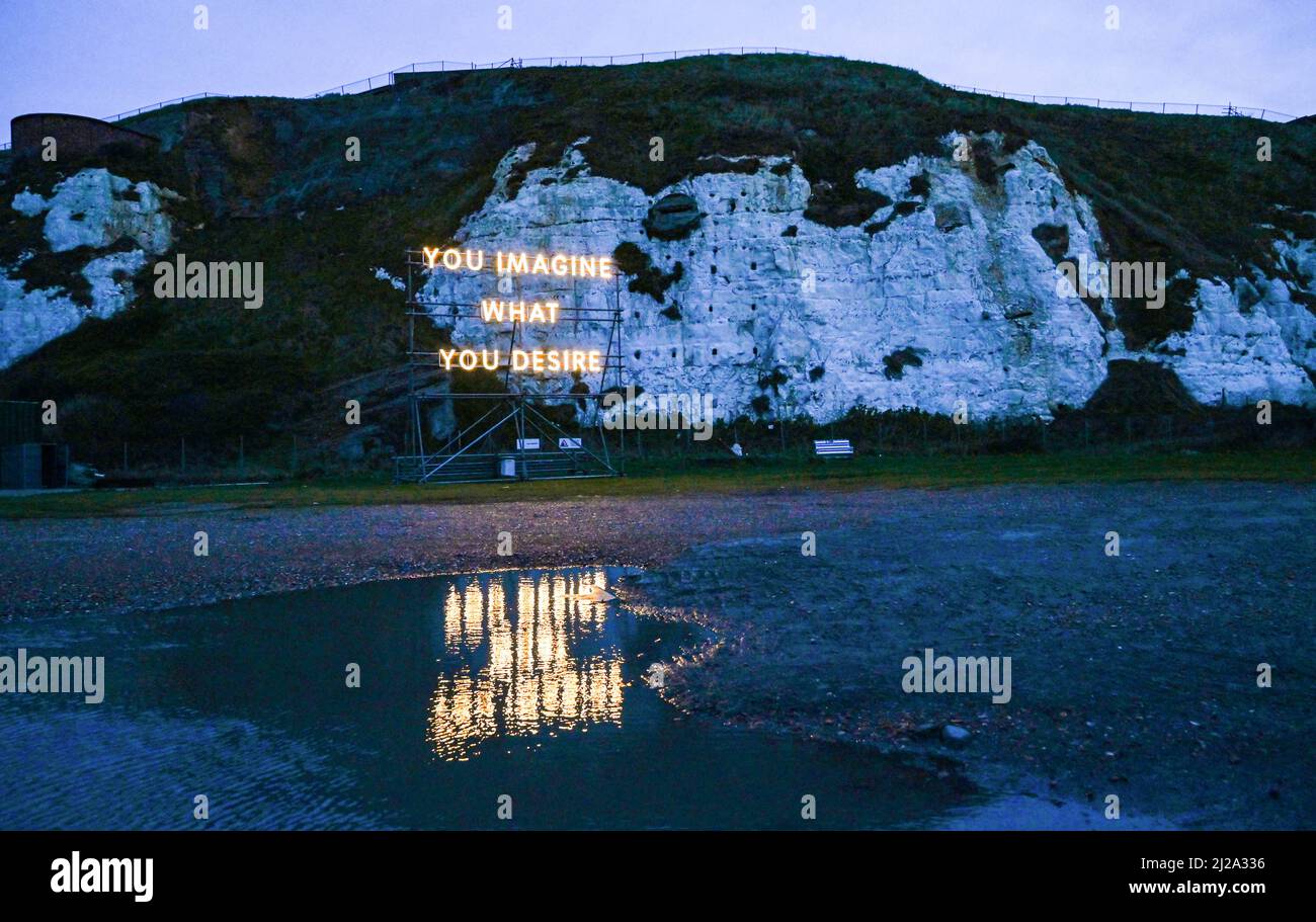 Newhaven UK 31st marzo 2022 - una scultura leggera con le parole 'You Imagine What You Desire' sotto le scogliere a Newhaven's West Beach, una delle sei sculture di luce all'aperto di Nathan Coley, una delle sei sculture di luce di Turner premiate, che illuminerà Sussex questa primavera : Credit Simon Dack / Alamy Live News Foto Stock