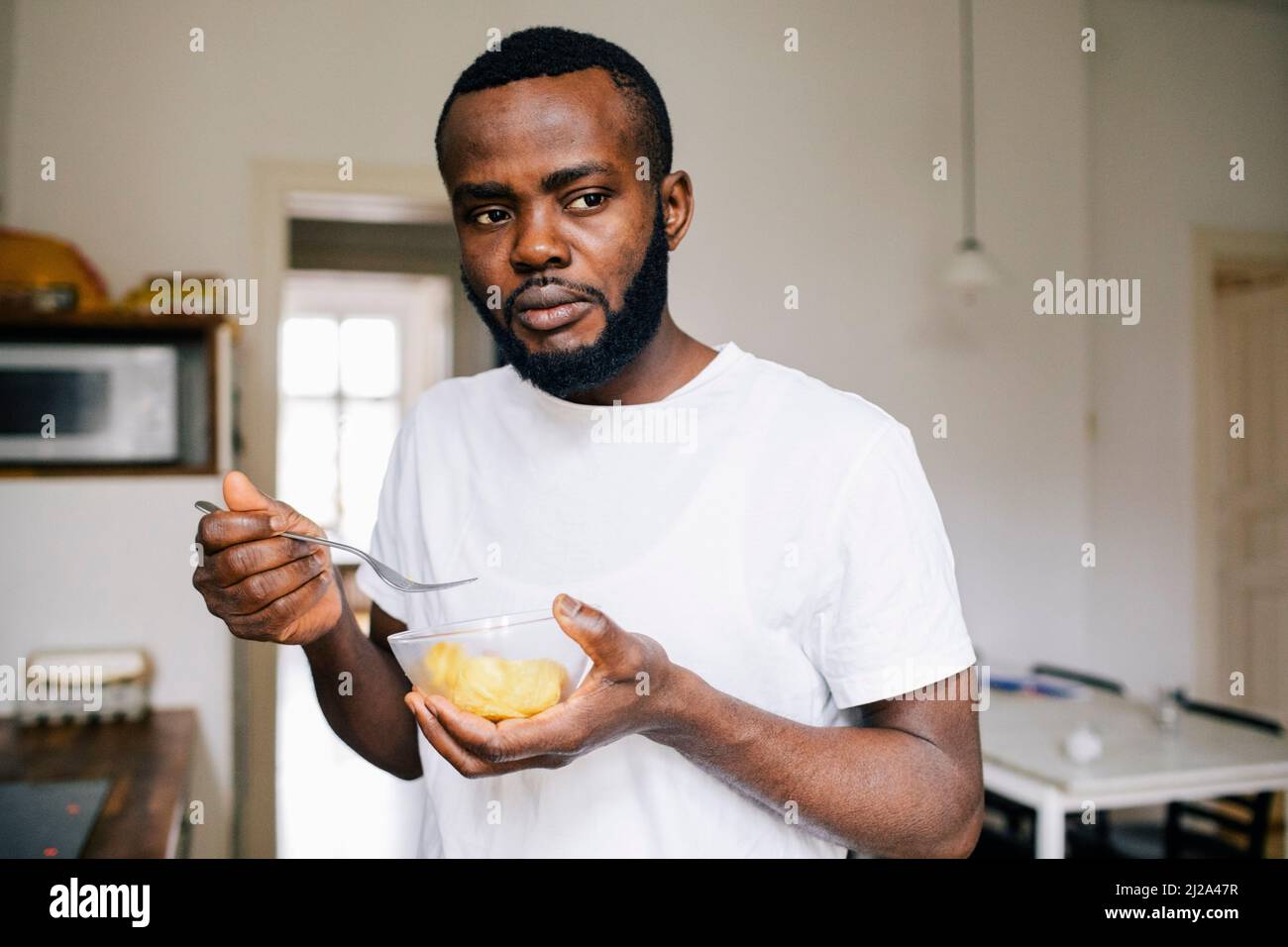 Uomo premuroso che guarda via mentre mangia da solo a casa Foto Stock