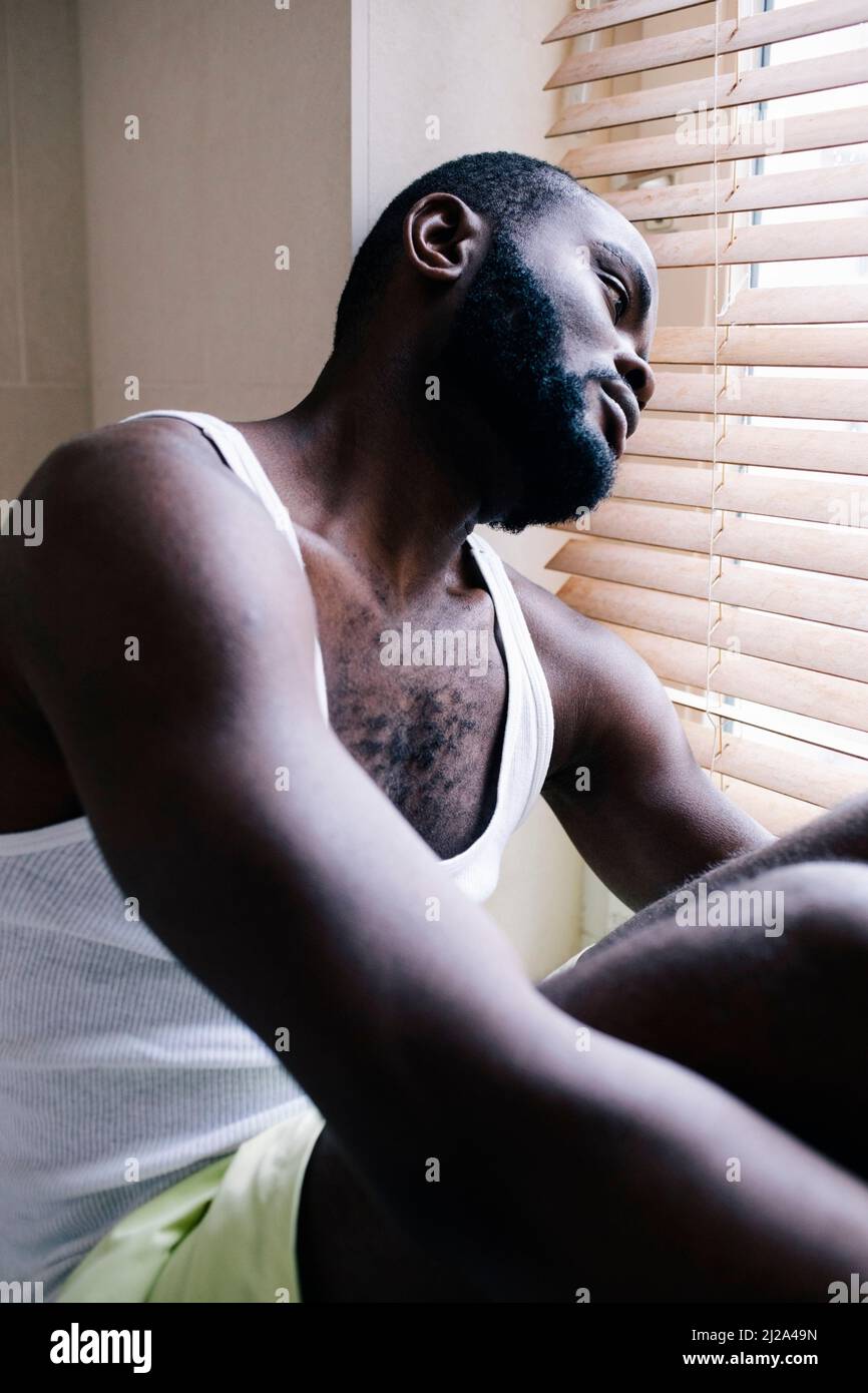 L'uomo solitario che soffre di depressione che si appoggia sui bui in casa Foto Stock