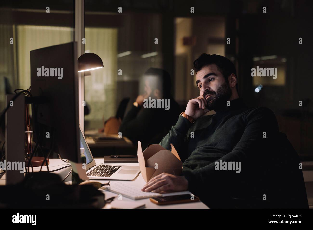 Uomo d'affari che lavora al computer all'ultimo minuto in ufficio di notte Foto Stock