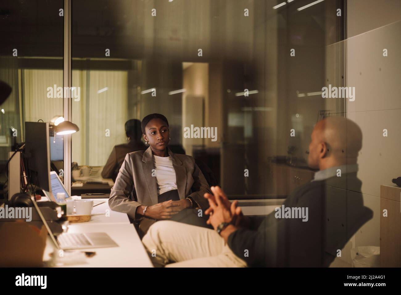 Strategia di pianificazione per uomini d'affari maturi con collega femminile visto attraverso vetro di ufficio Foto Stock