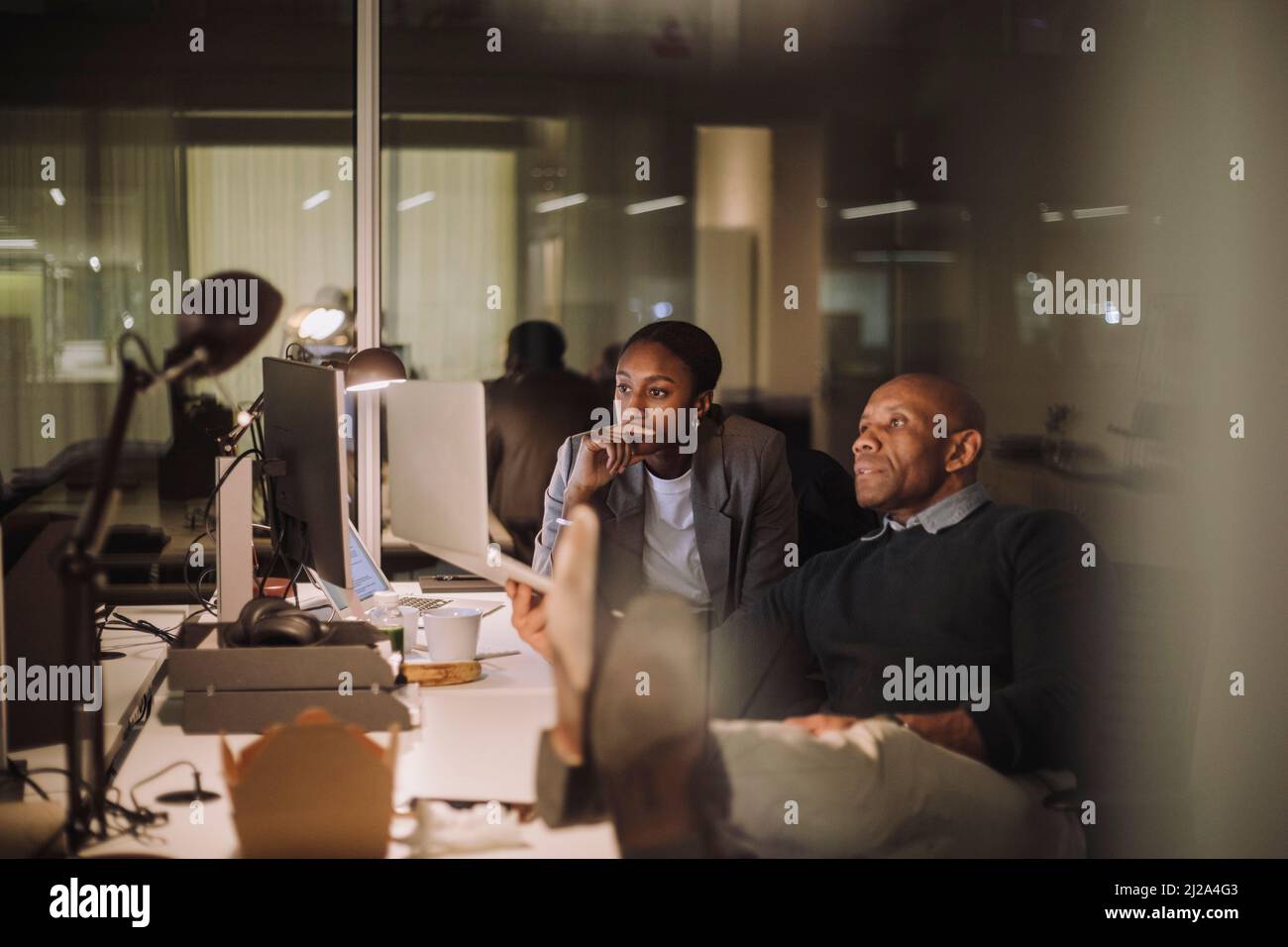 Colleghi uomini e donne ambiziosi che discutono di notte in ufficio con un notebook Foto Stock