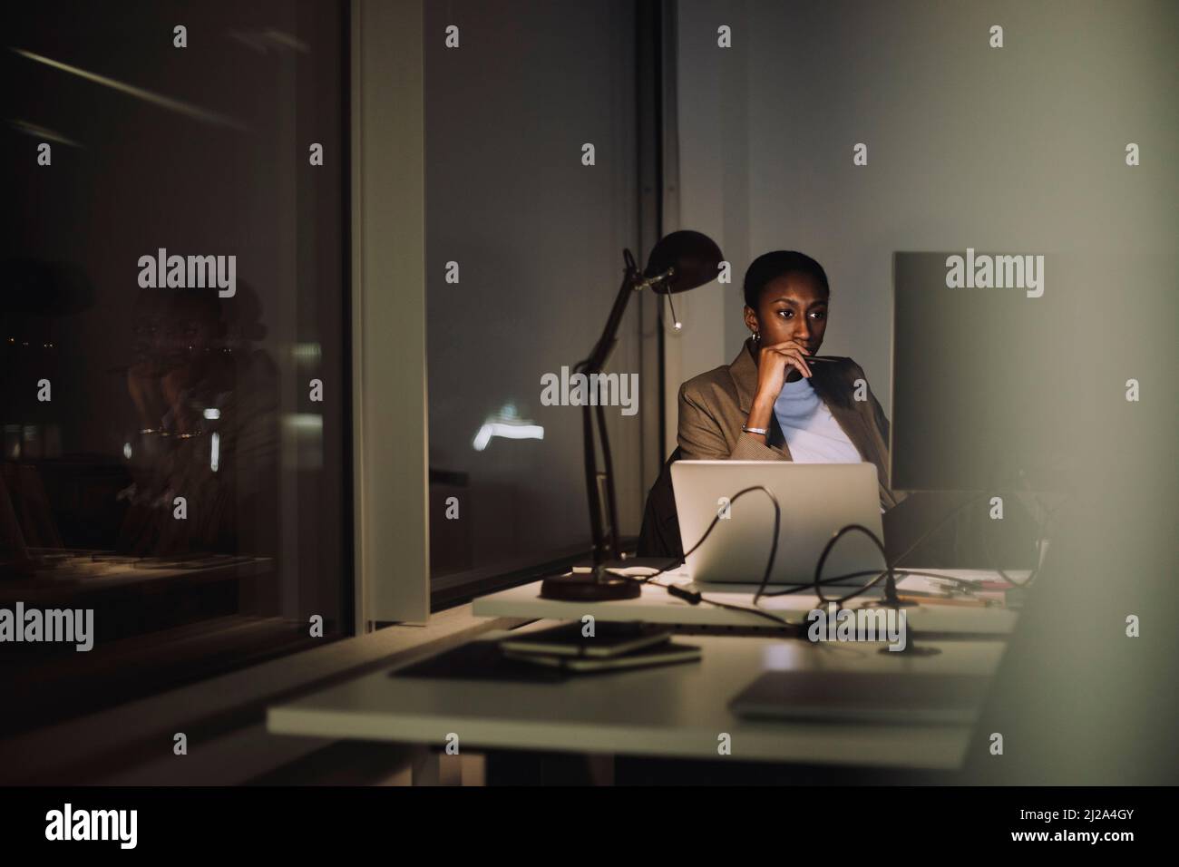 Donna d'affari che usa il computer mentre lavora all'ultimo minuto in ufficio di notte Foto Stock
