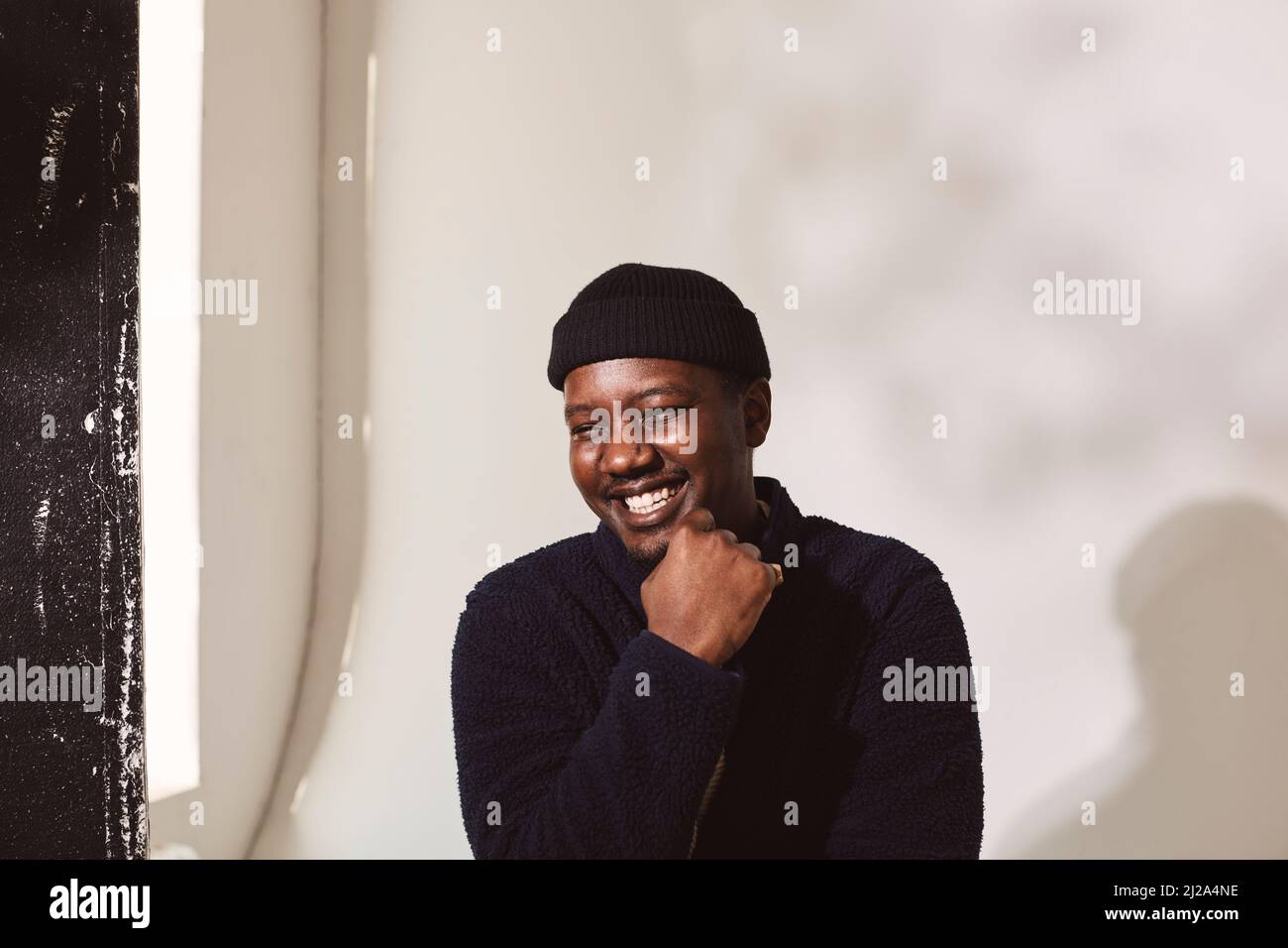 Uomo felice con mano sul mento contro il muro bianco Foto Stock