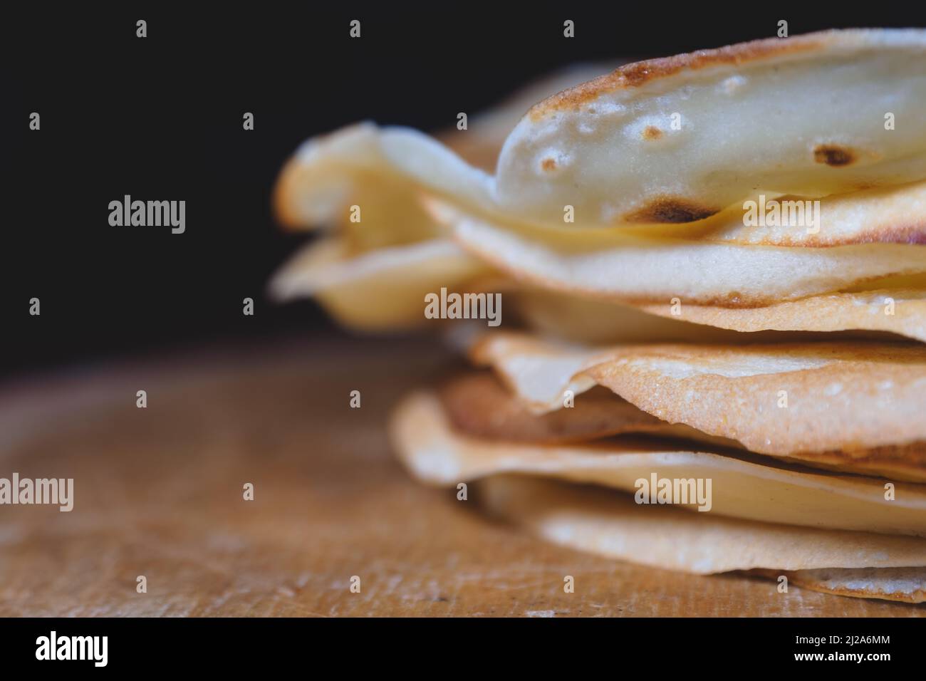 Primo piano di pancake appena sfornati impilati su un asse di legno Foto Stock